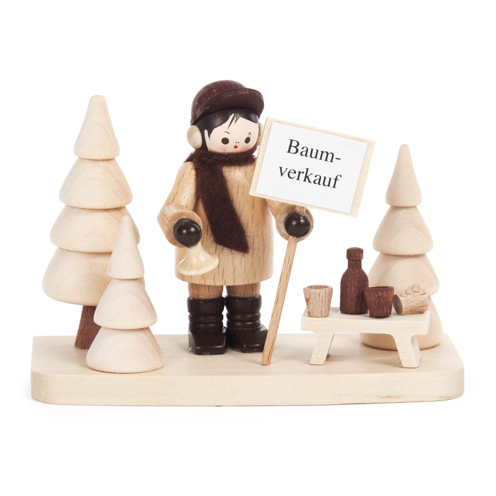 Holzfigur eines Verkäufers mit Schal und Mütze, der ein Schild mit 'Baumverkauf' hält. Umgeben von Holzbaumattrappen, auf einem Stand mit Bechern und Flaschen. im Dregeno Online Shop günstig kaufen