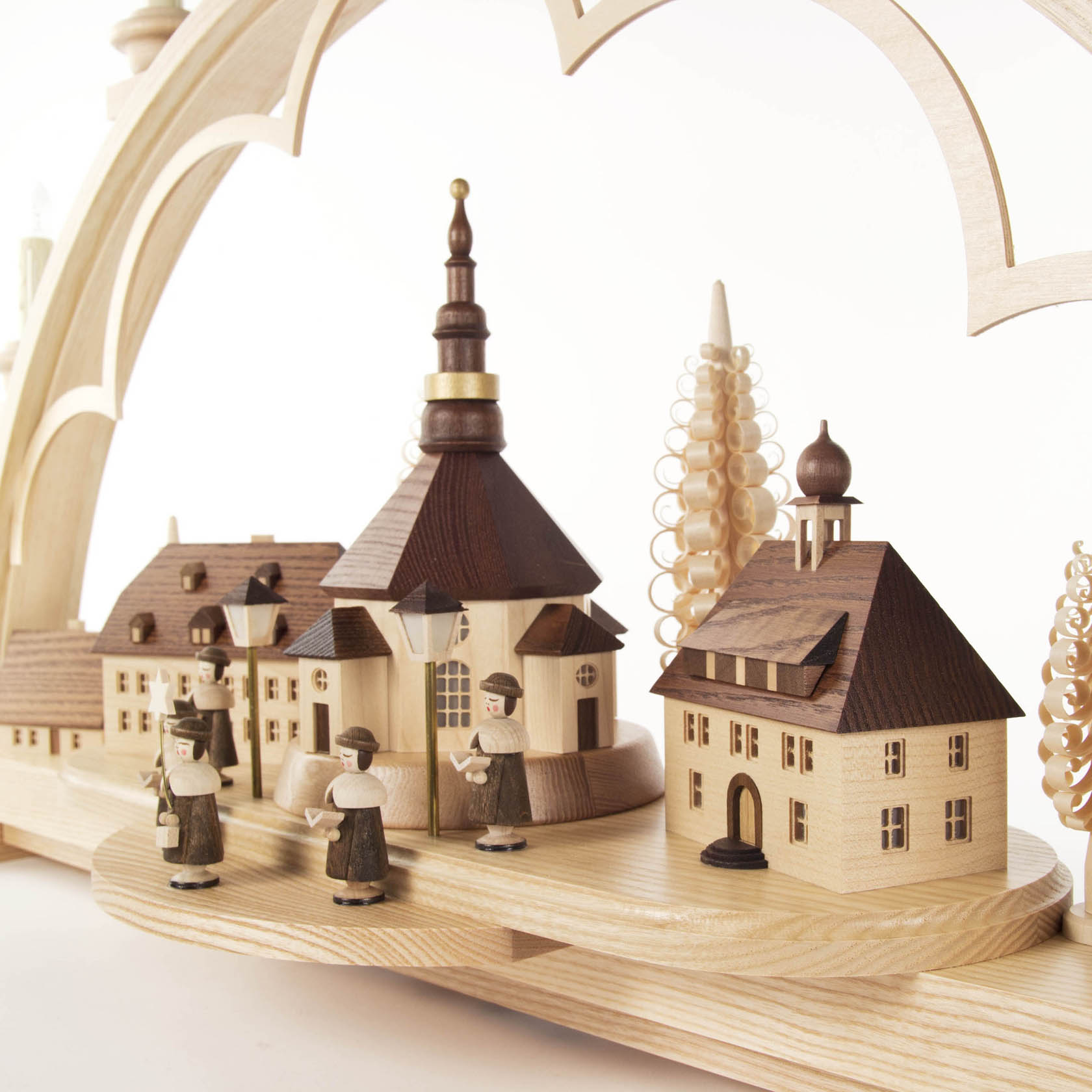 A wooden arch with a scene depicting the Seiffen village and Kurrende choir, featuring electrically lit, illuminated buildings.