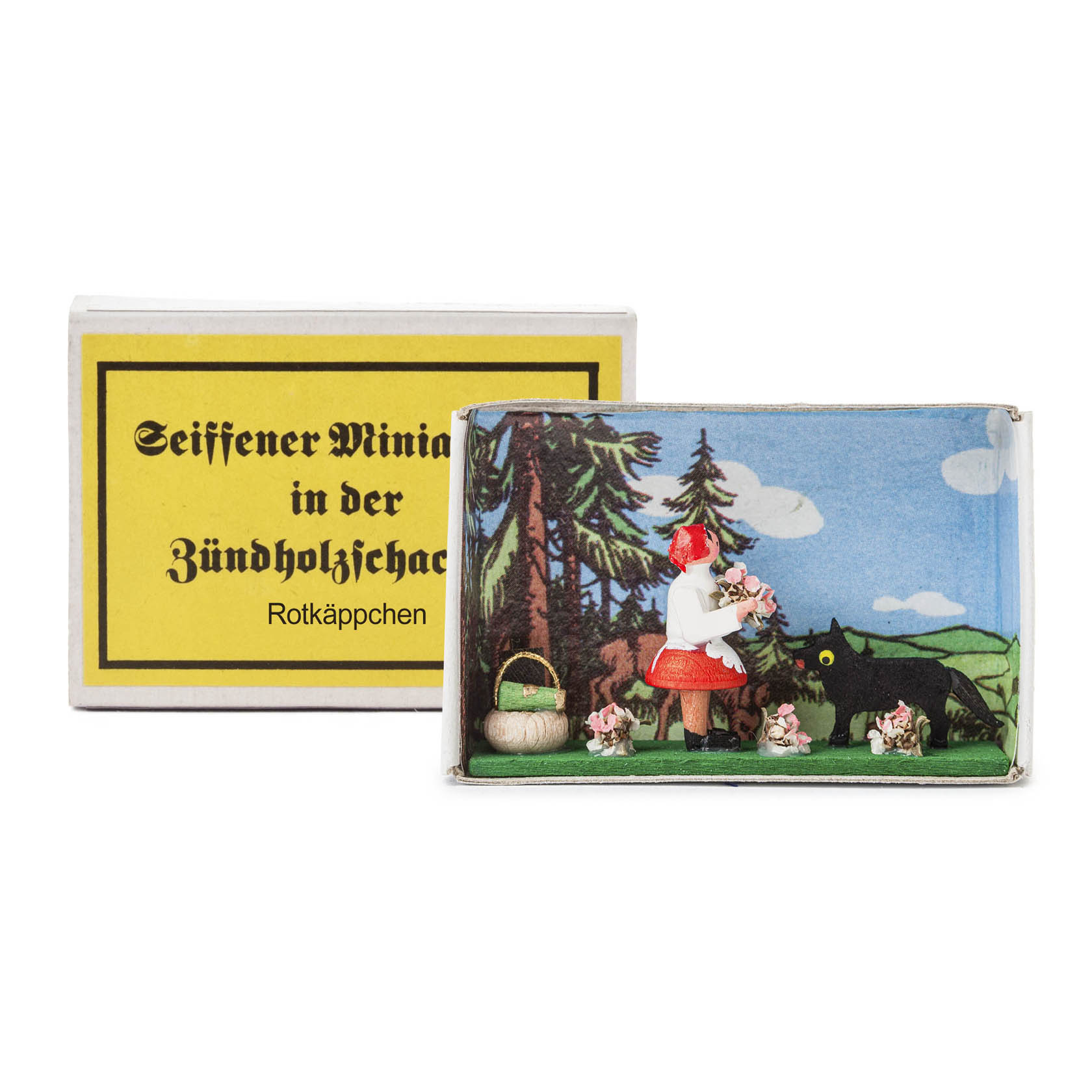 A miniature scene in a matchbox showing Little Red Riding Hood with a wolf in the background and small animals surrounding her. im Dregeno Online Shop günstig kaufen