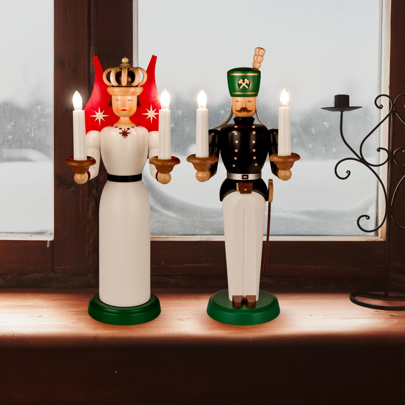 Elektrisch beleuchtete Holzfiguren Engel und Bergmann, 40 cm hoch, auf Fensterbank. Beide halten Kerzen, Engel in weißem Kleid, Bergmann in schwarzer Uniform.