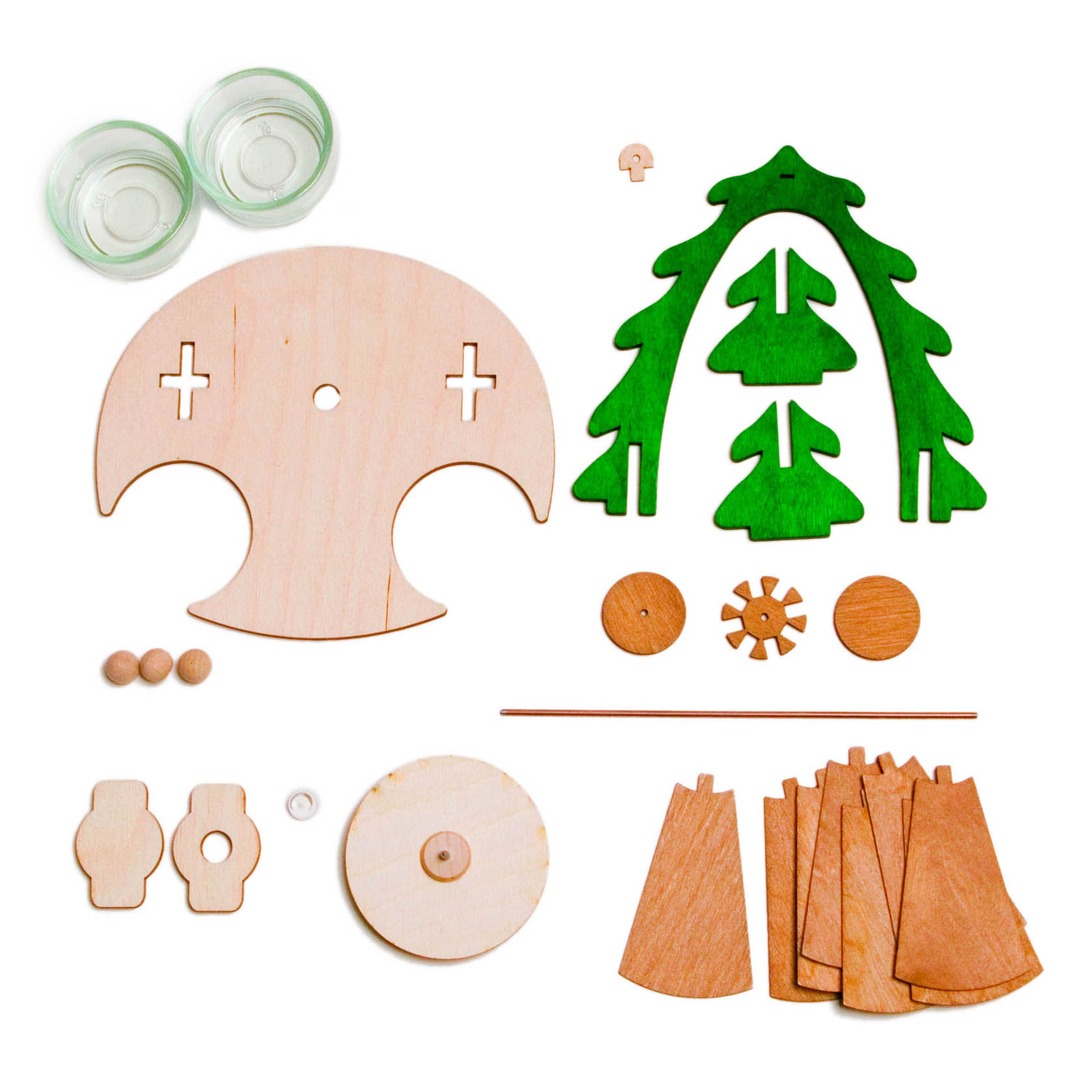 Components of a DIY pyramid set including wooden cutouts in various shapes, green tree pieces, small glass holders, and wooden balls.