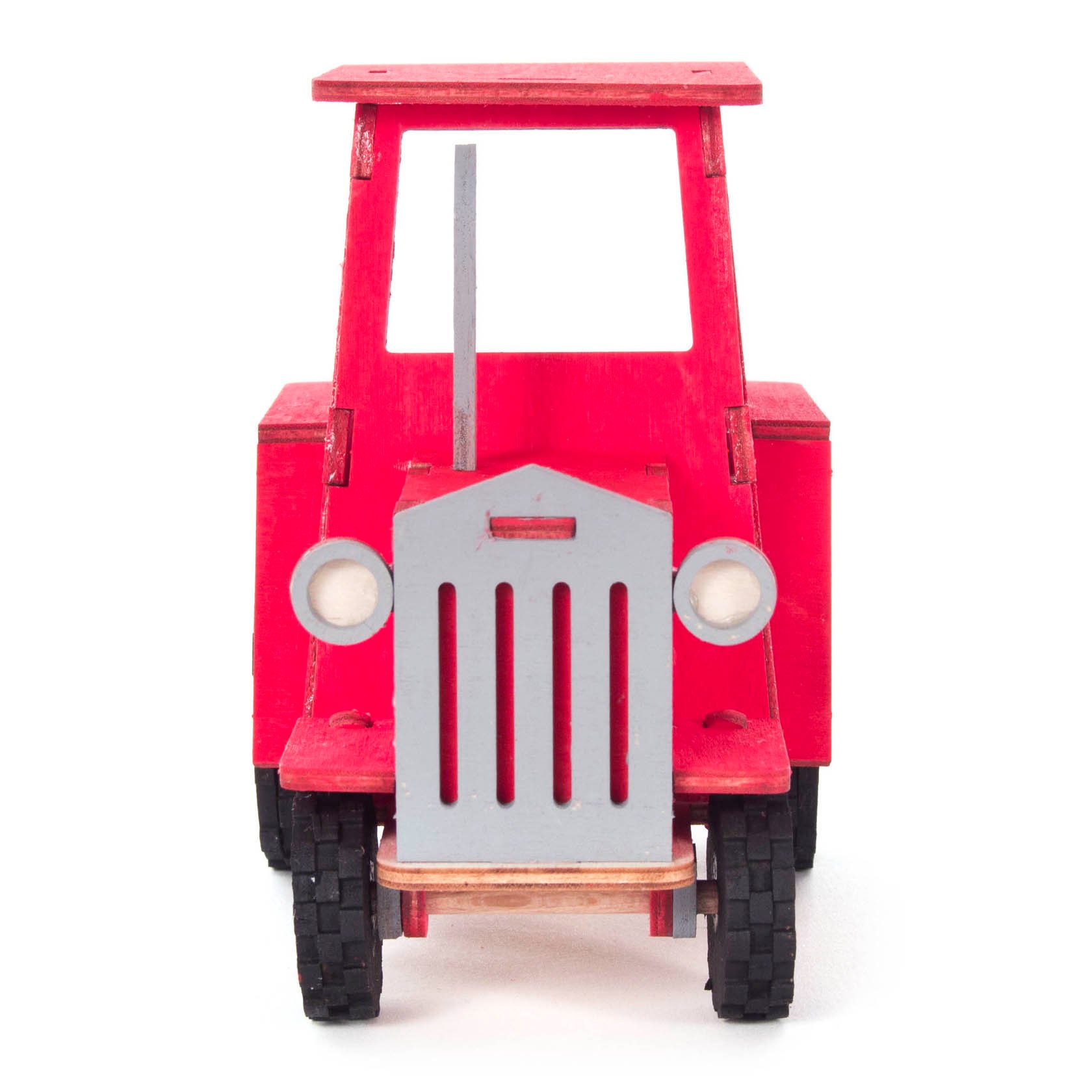 A small red toy tractor model with a simplistic design, featuring a flat rectangular top, circular headlights, and black wheels on a white background.