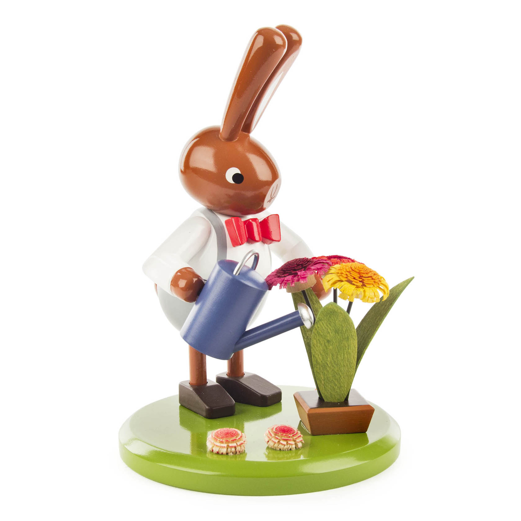 Wooden rabbit figurine wearing a white coat and red bow tie, holding a blue watering can, watering colorful flowers on a green base.