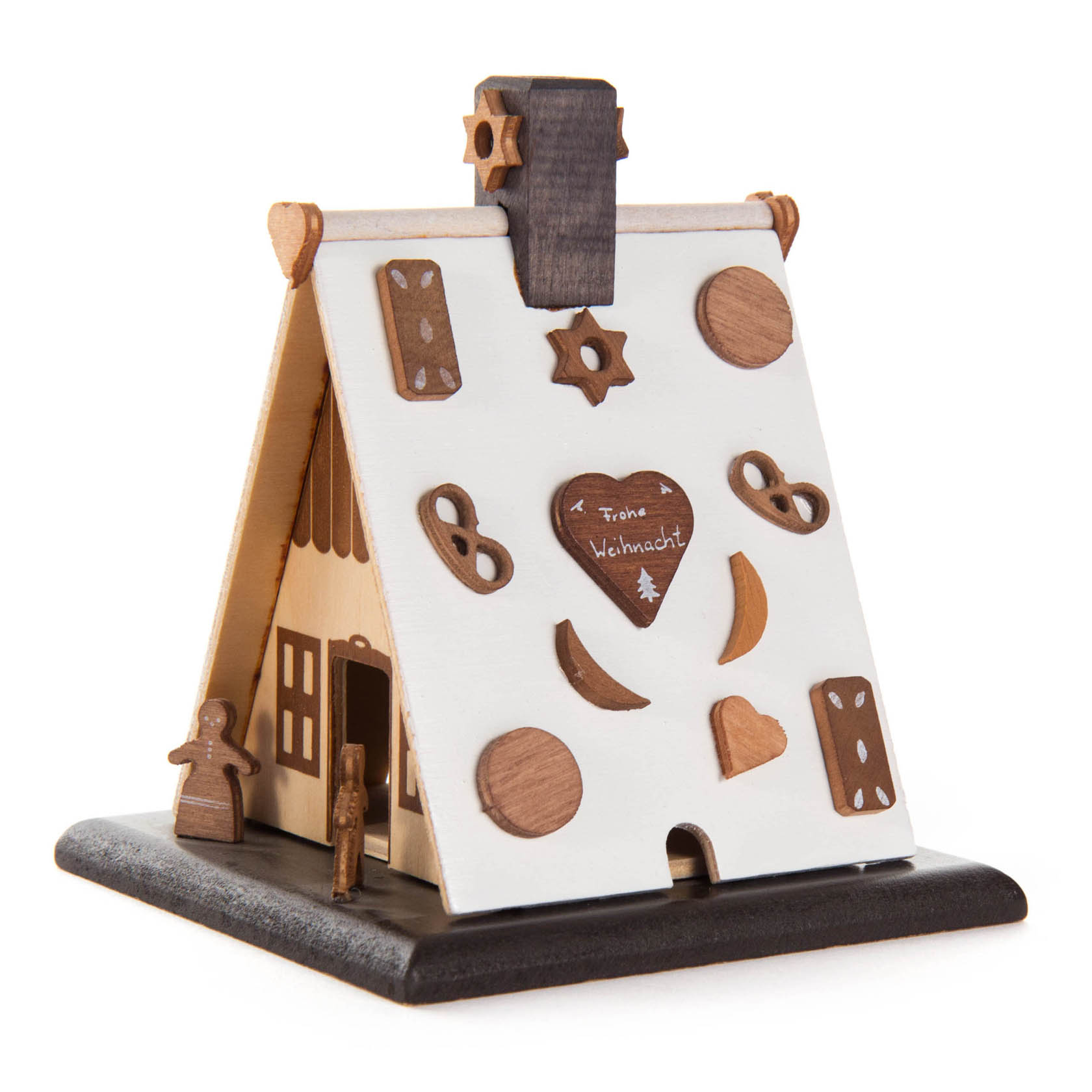 Ein kleines, dreidimensionales Bastelset eines Knusperhauses aus Holz mit weißer und brauner Bemalung. Es hat eine Herzform mit "Frohe Weihnacht" Schriftzug.
