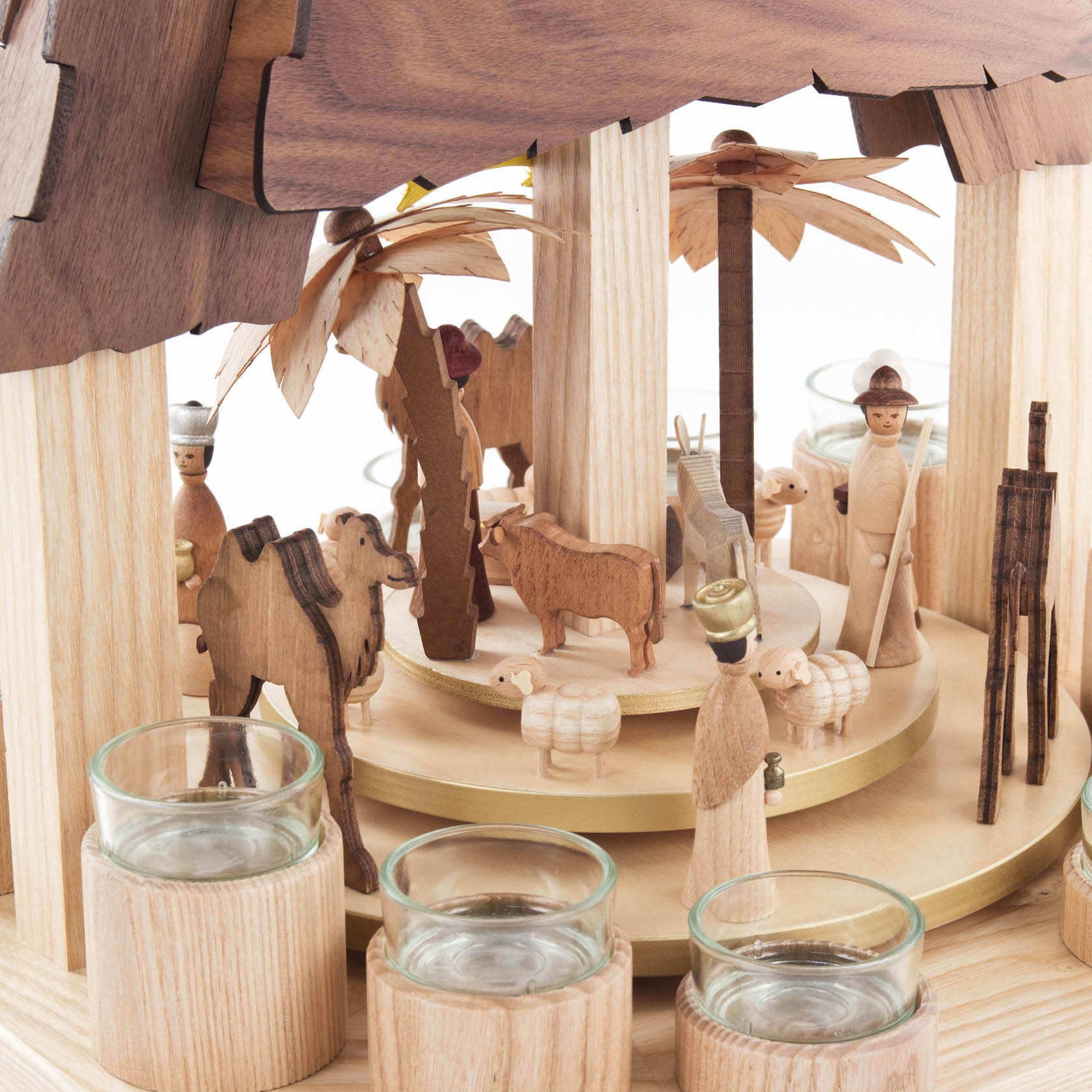 Wooden nativity pyramid with two propeller wheels, featuring figures of Mary, Joseph, baby Jesus, shepherds, sheep, camel, and a donkey, with tealight holders.