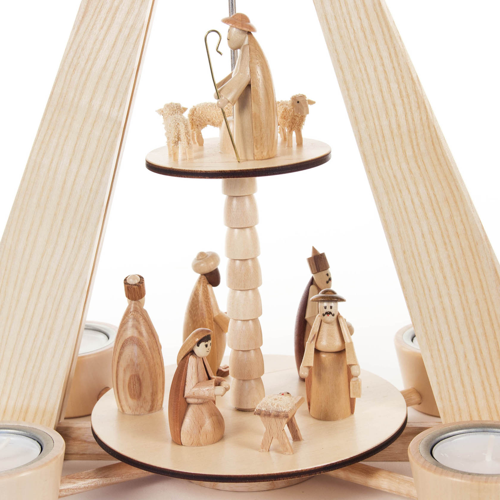 Zweistufige Pyramide aus Holz mit Szenen der Geburt Christi: Oben ein Hirte mit Schafen, unten Maria, Josef, Krippe und drei Heiligenfiguren, umgeben von Teelichthaltern.