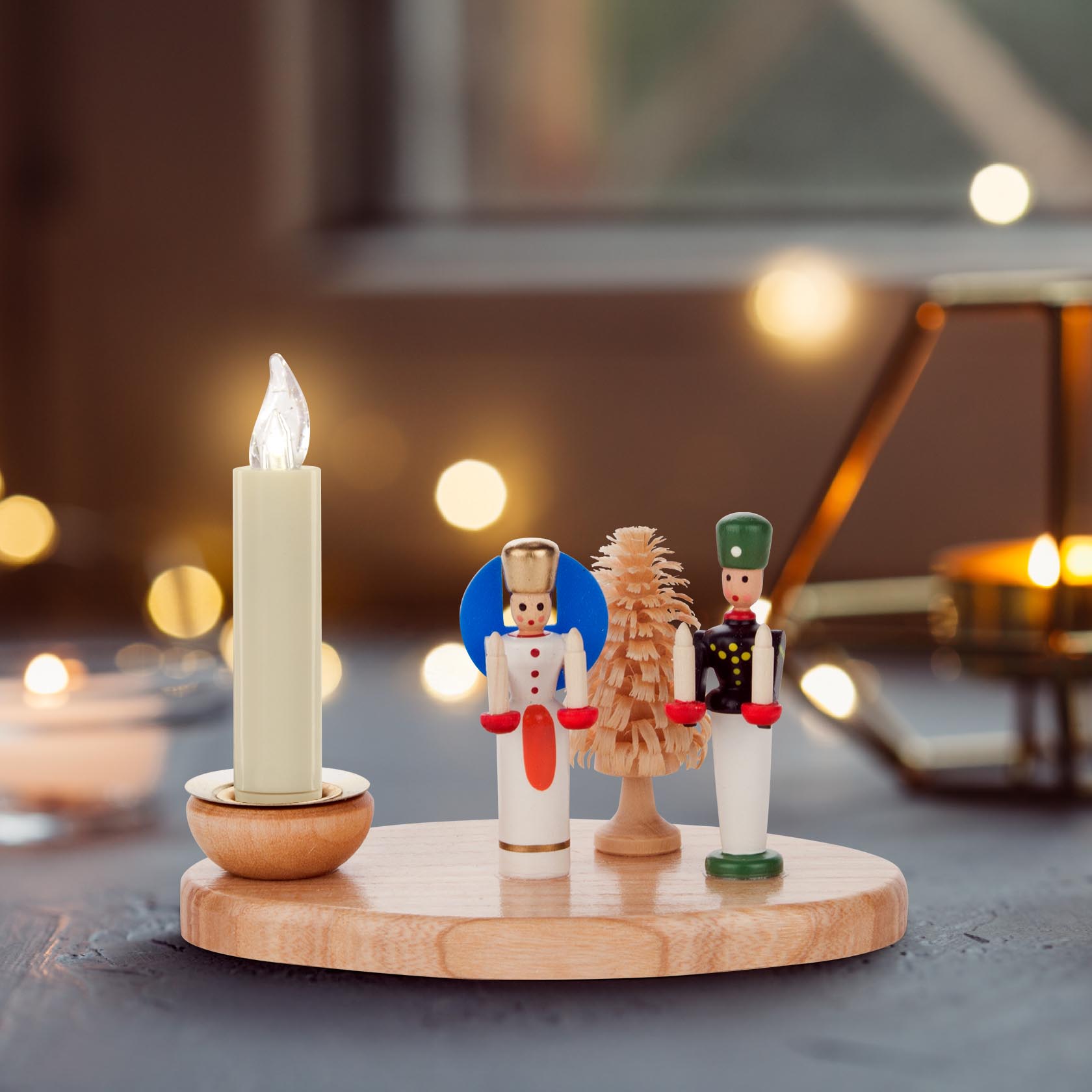 Holzkerzenhalter mit einer geschmückten weißen LED-Kerze, zwischen einem Engel in blau-goldener Kleidung und einem Bergmann in grüner Uniform, beide aus Holz.