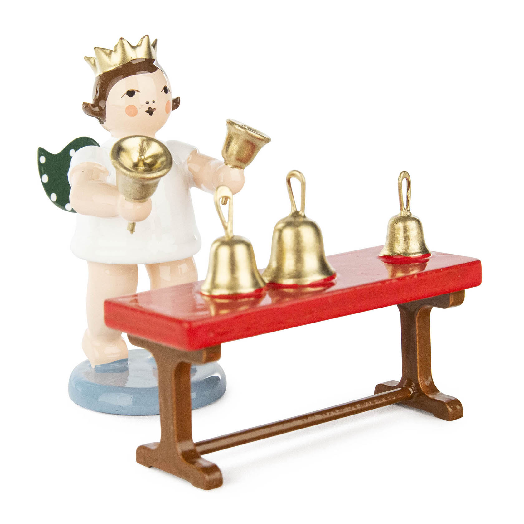 A smiling angel figurine with a golden crown and wings, playing a handbell and standing next to a red table with three golden bells. im Dregeno Online Shop günstig kaufen