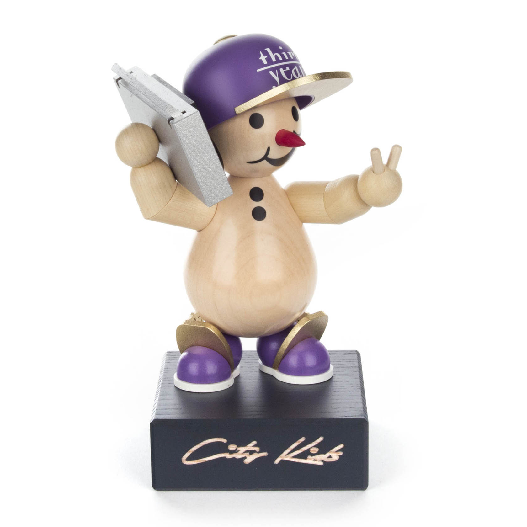 Holzfigur eines Schneemanns mit lilafarbener Baseballkappe, boombox und violetten Schuhen, der ein Peace-Zeichen macht. Auf dem Sockel steht 'City Kids'.