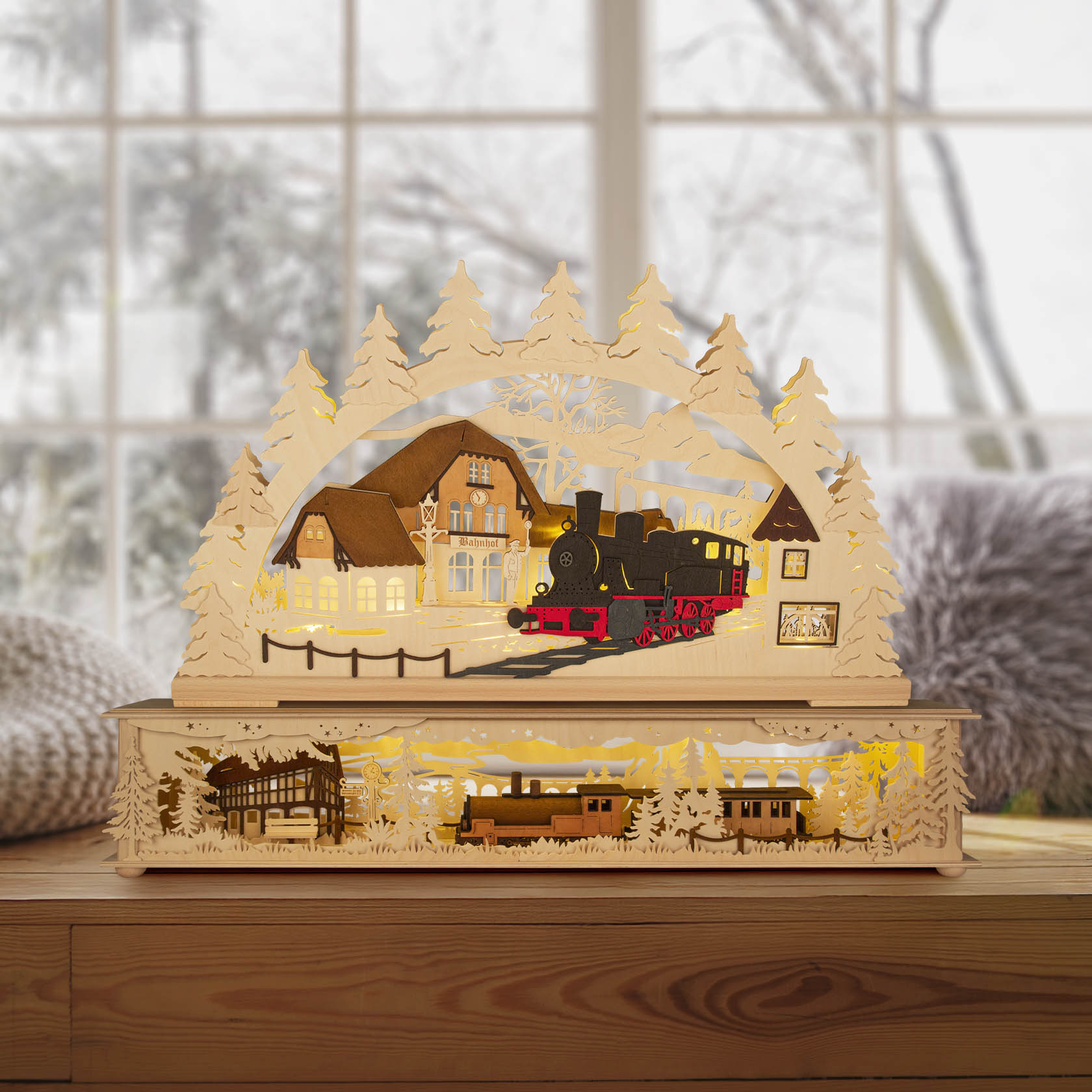 A wooden arch candle holder featuring a train station with a steam locomotive and LED lighting, surrounded by trees, sitting on a windowsill.