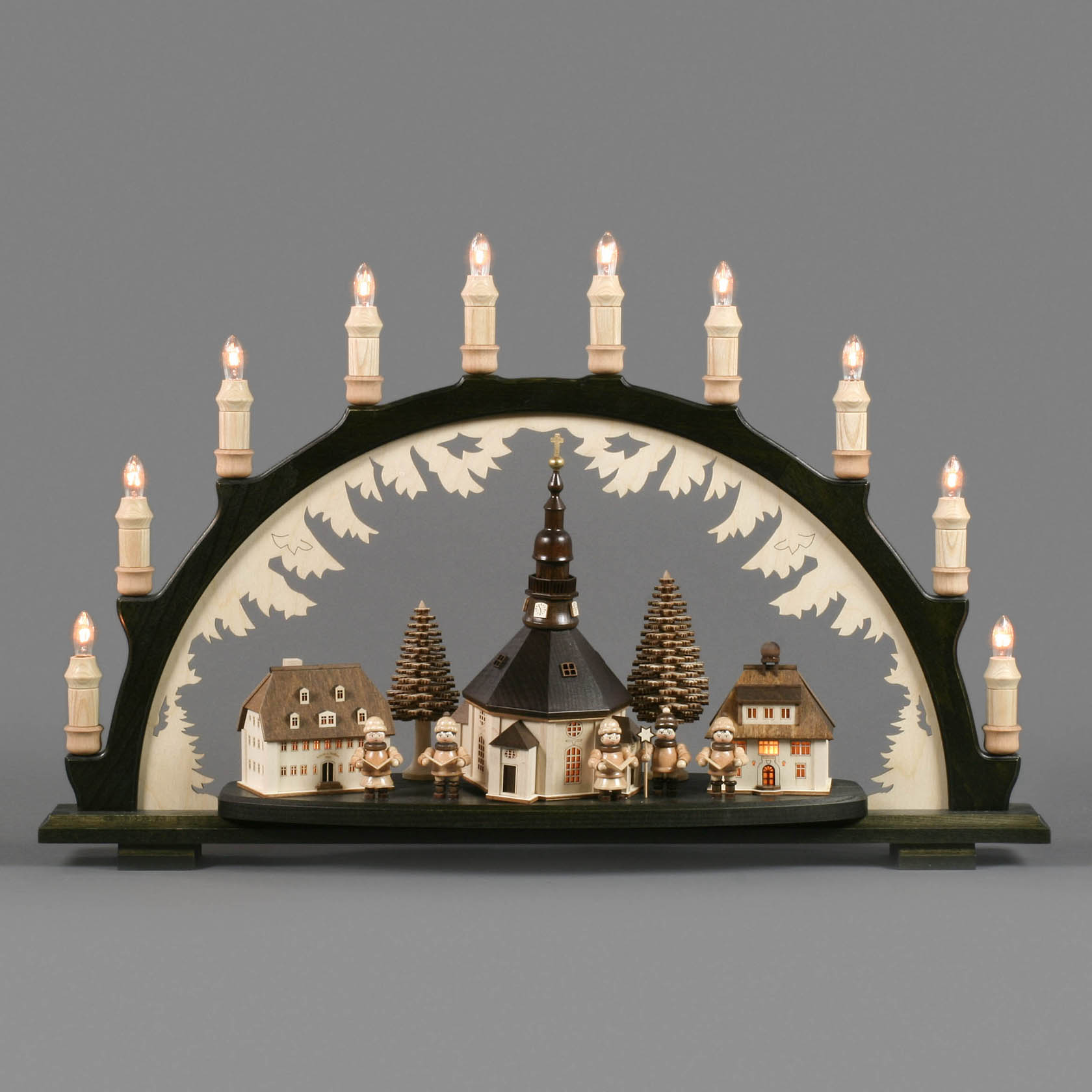 A black Schwibbogen arch with Seiffener village and Christmas singers, featuring LED-lit buildings. Decorative arch with candles on top.