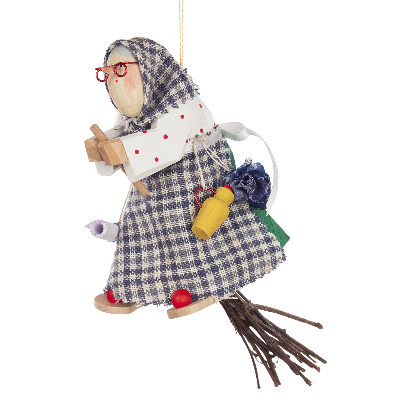 Holzfigur einer geschnitzten Kräuterhexe mit roter Brille, blau-weiß karierter Kleidung und einem Besen. Sie hält ein Buch und hat Accessoires wie Kräuter und Fläschchen.