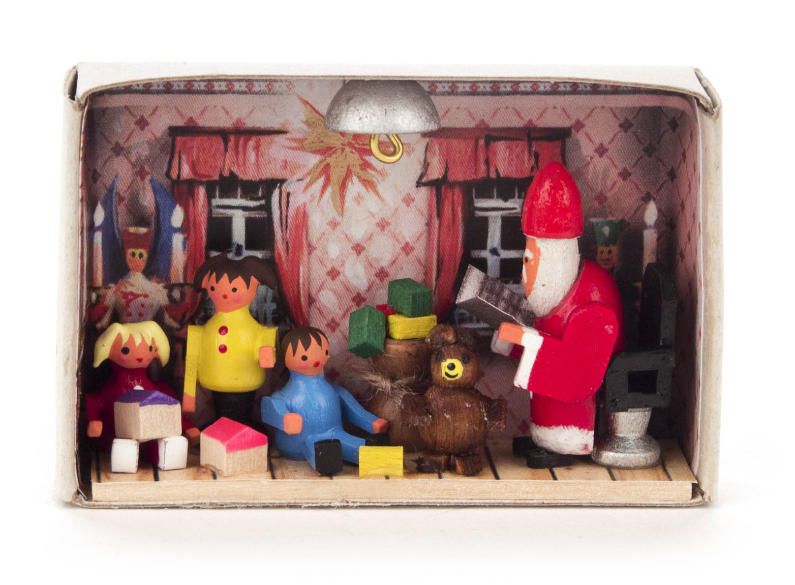 Miniaturszene in einer Zündholzschachtel: Ein Weihnachtsmann liest einer Gruppe von Kindern und einem Bären unter einer Lampe in einem Zimmer mit rosa Vorhängen vor.