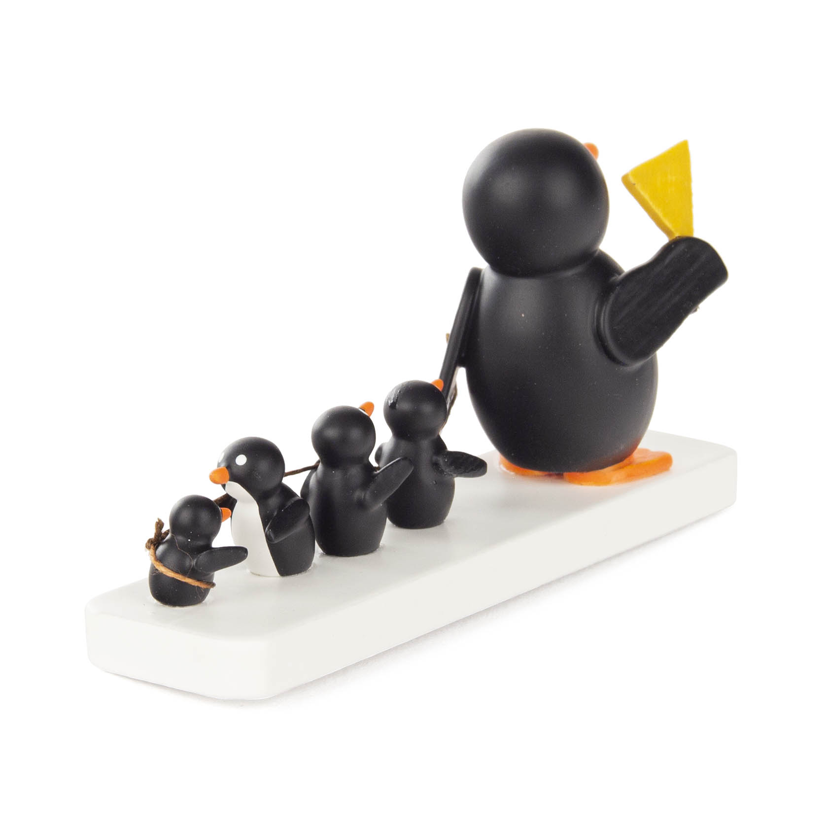 A line of four small black penguin figures with orange beaks and feet on a white base, the first holding a yellow flag.