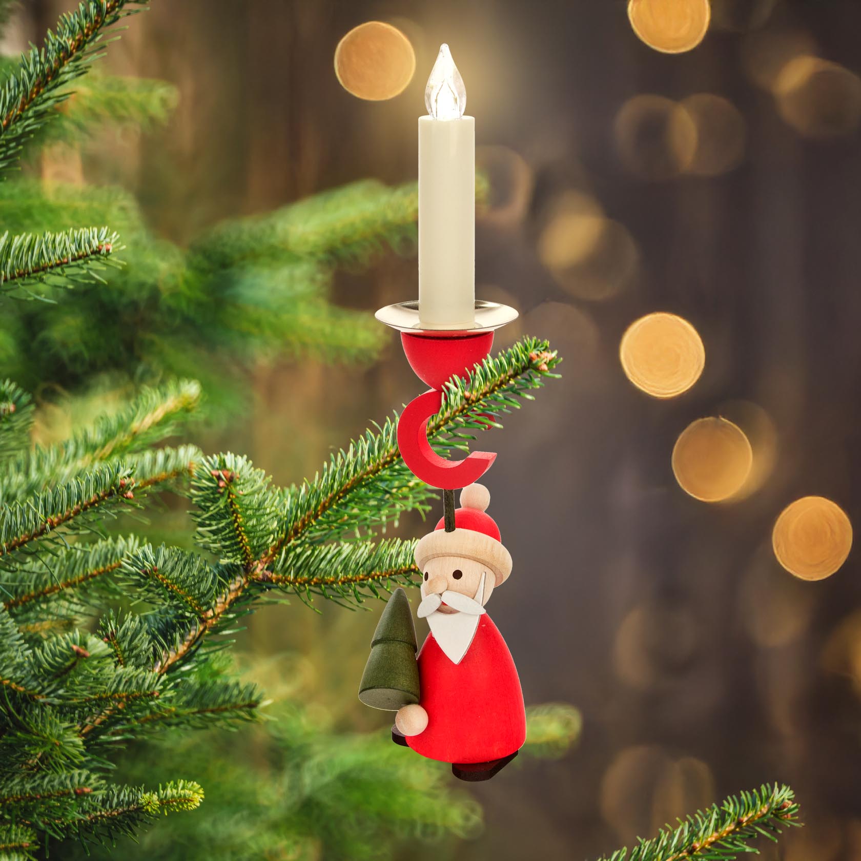 Ein Kerzenhalter in Form von Ruprecht, einem Weihnachtsmann, hängt an einem grünen Tannenzweig. Der Halter trägt eine brennende Kerze mit einer Fassung für 14 mm Kerzen.