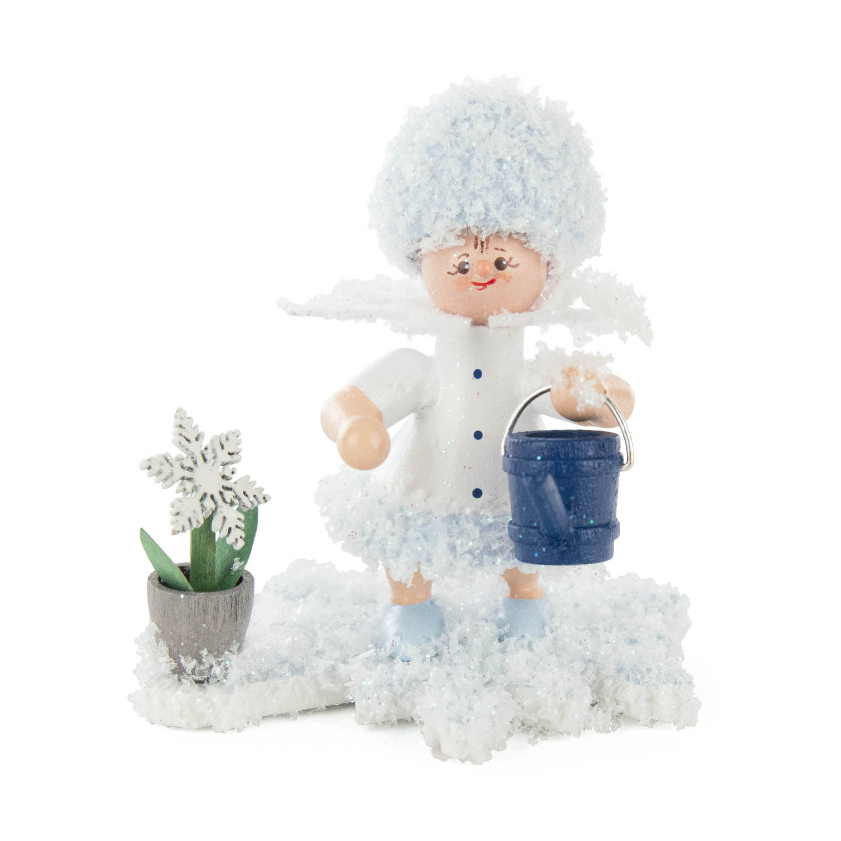A small figurine of a girl with snow-covered hair, wearing a white coat and holding a blue watering can, standing next to a pot with a snowflake plant. im Dregeno Online Shop günstig kaufen