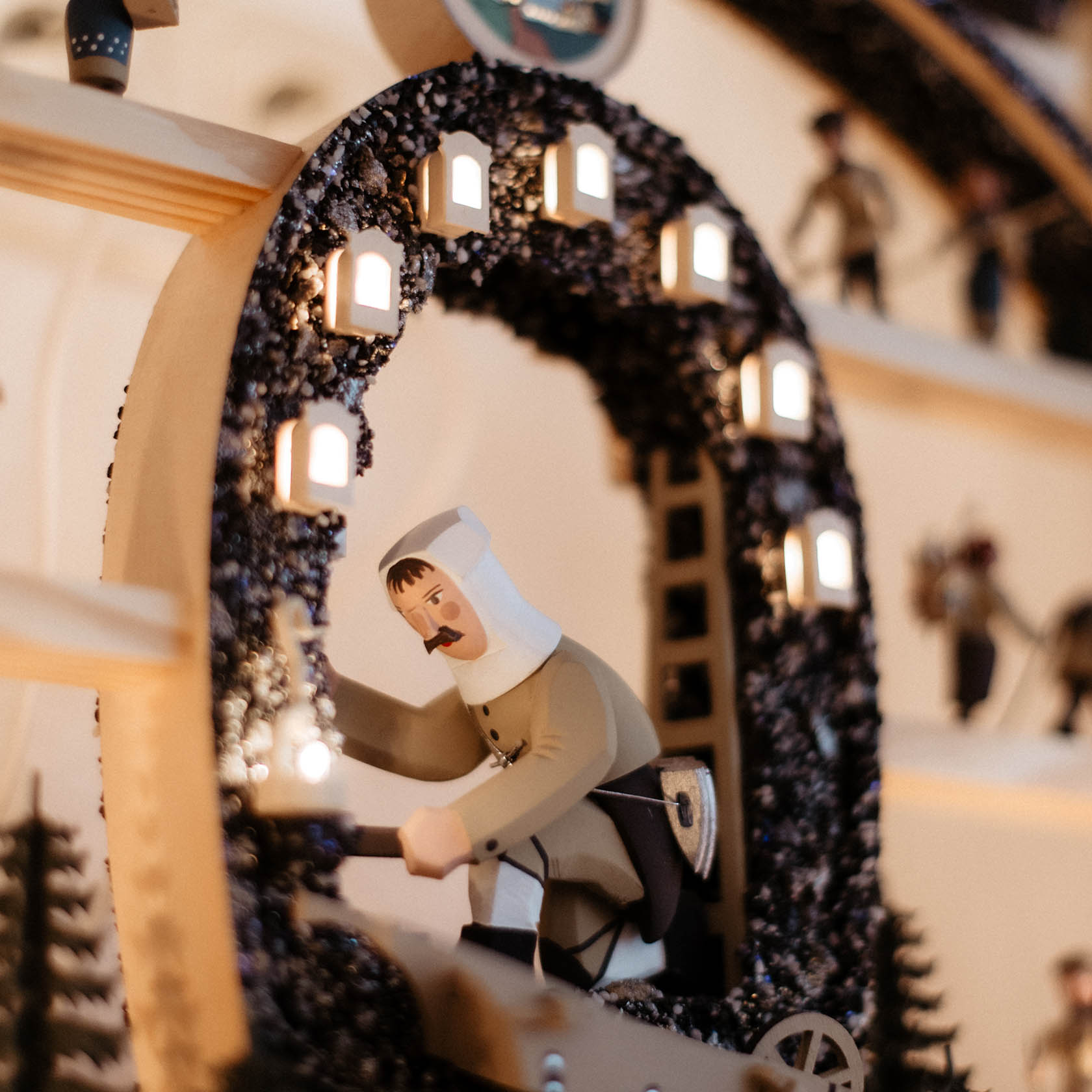 Ein traditioneller hölzerner Schwibbogen zeigt einen Bergmann mit Grubenlampe. Der Bergmann ist detailliert geschnitzt und in typischer Kleidung dargestellt.