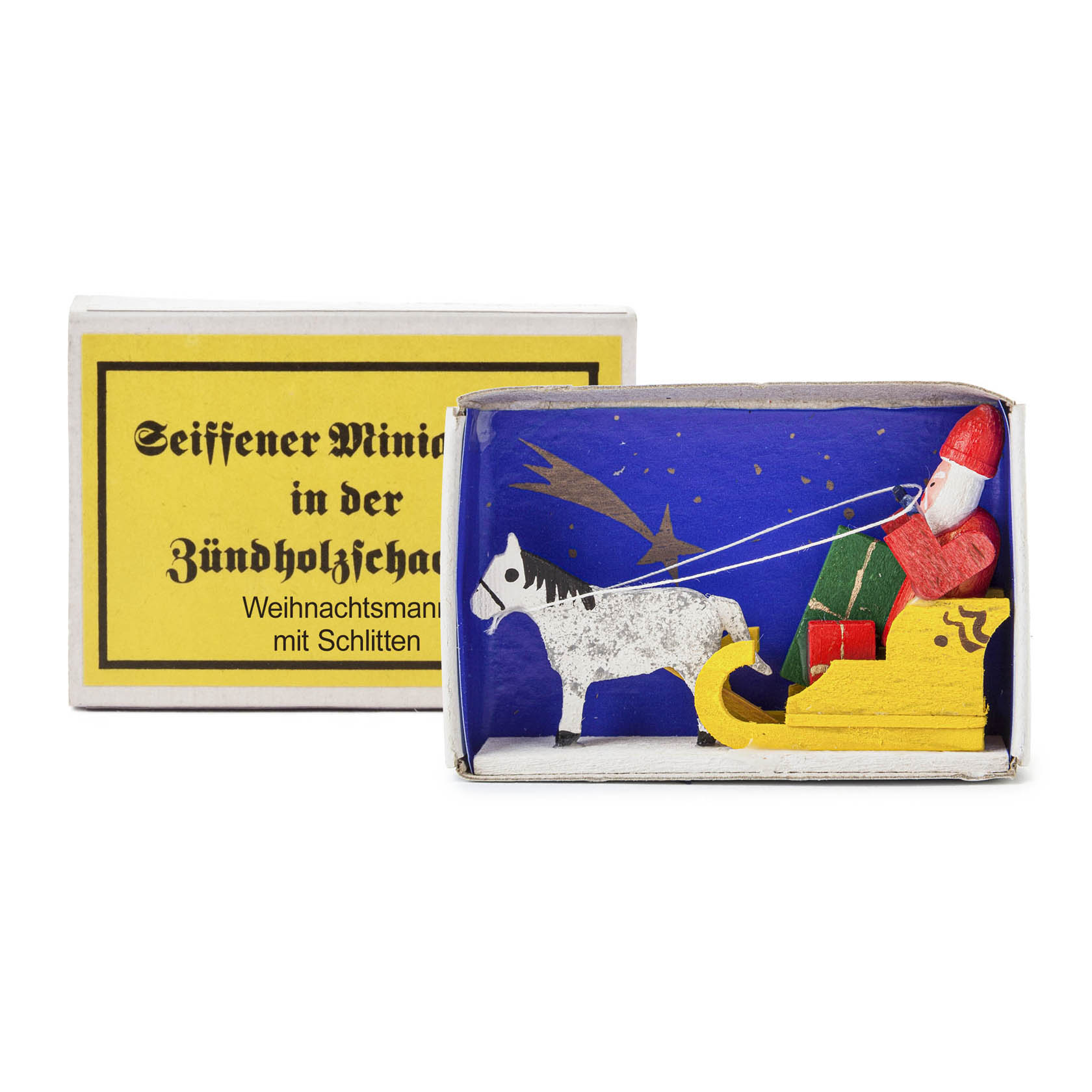 A matchbox containing a miniature wooden figure of Santa Claus in a sleigh being pulled by a horse, with gifts in the sleigh.