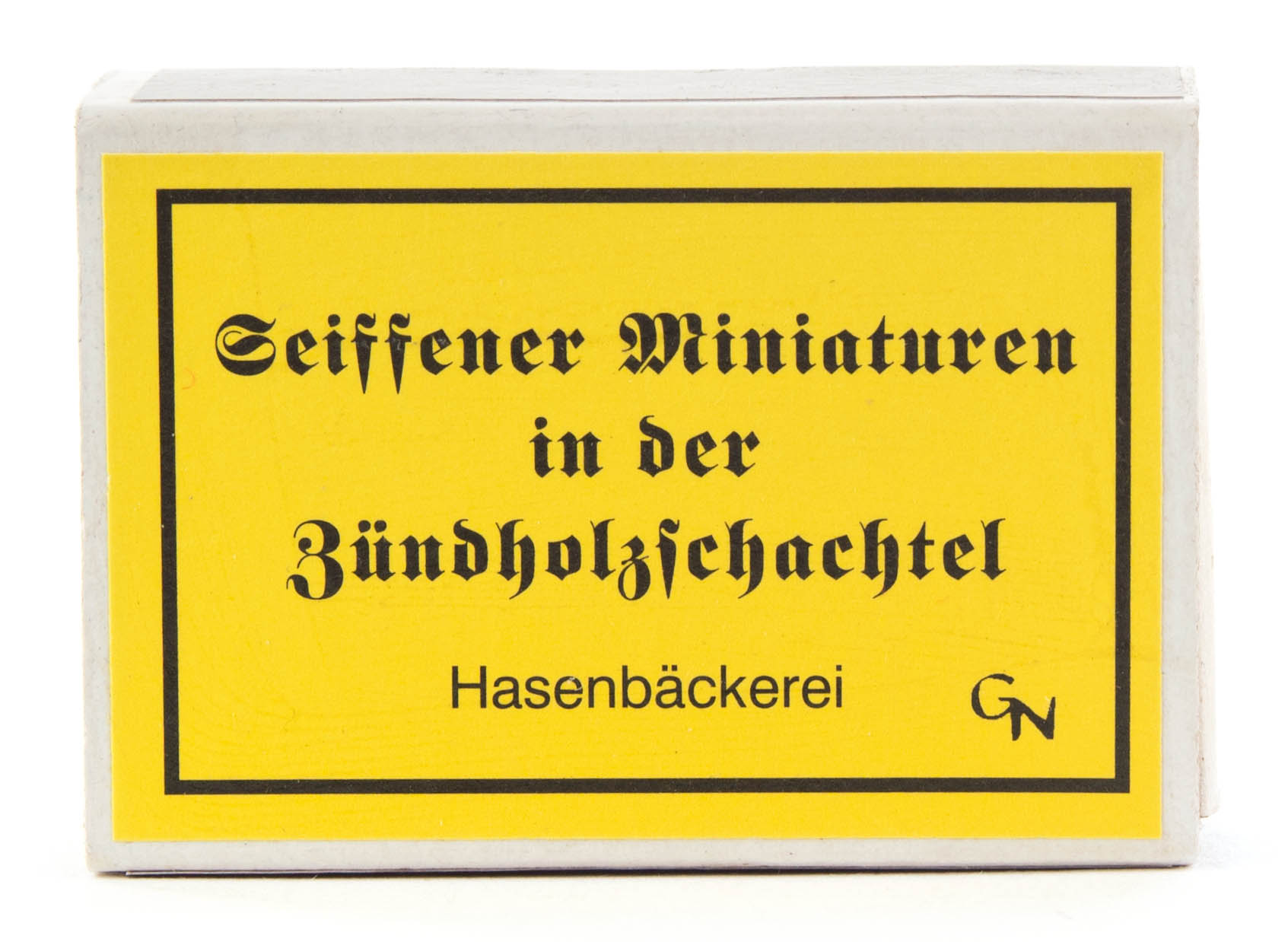 A yellow matchbox labeled 'Seiffener Miniaturen in der Zündholzschachtel Hasenbäckerei' with a 'GN' logo.