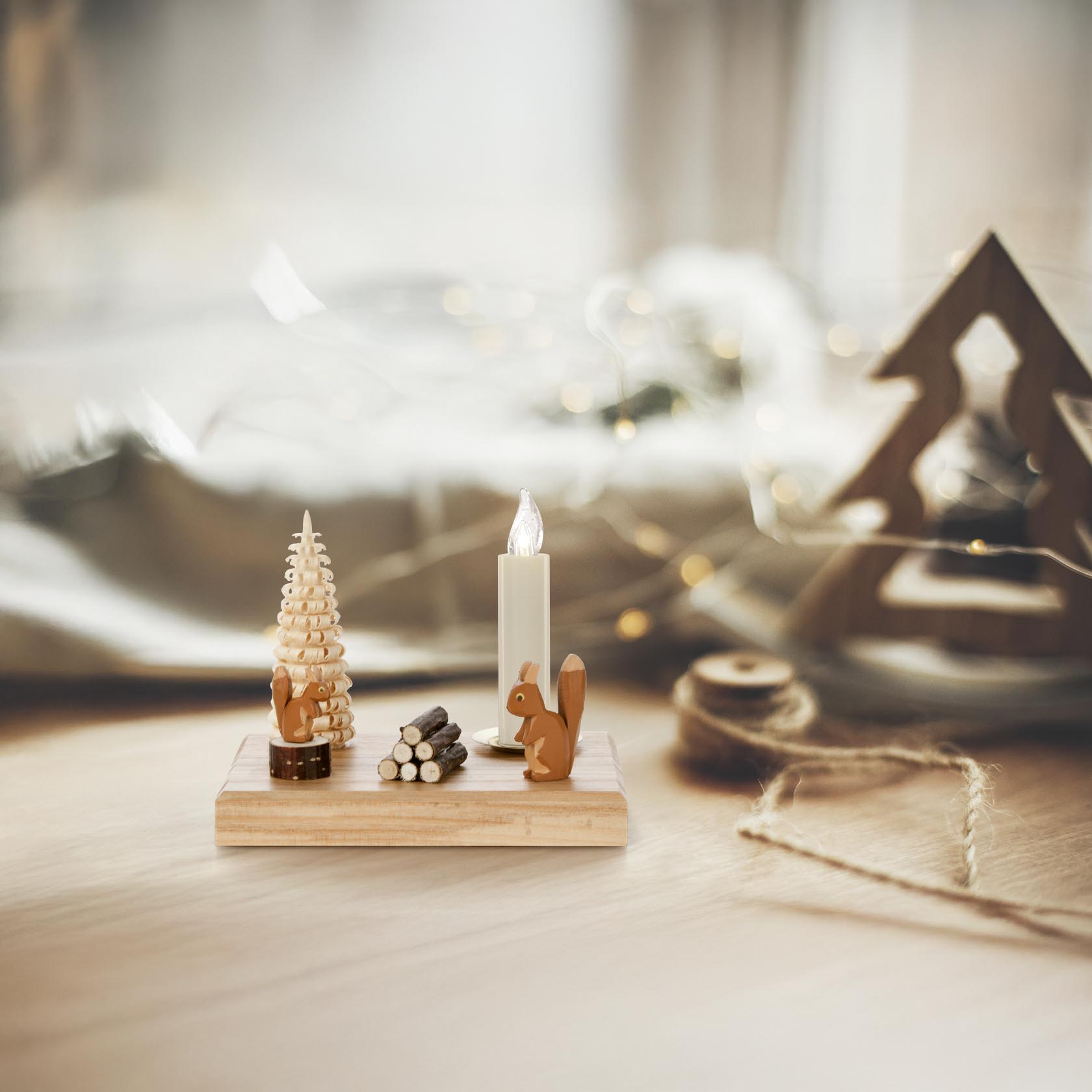A wooden candle holder featuring a squirrel figure and a candle with a diameter of 14mm, accompanied by a small pine tree sculpture.