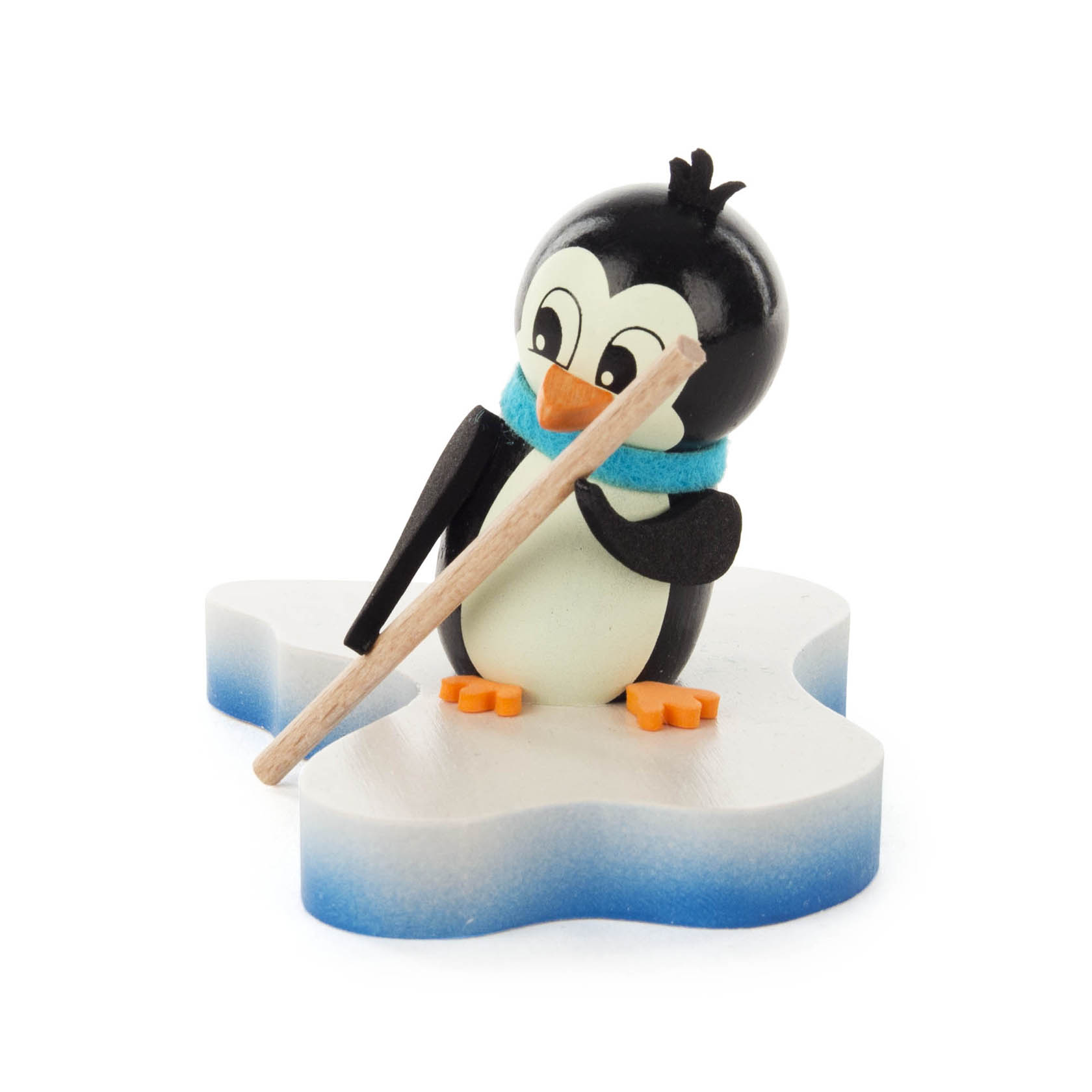 A small, cute wooden penguin figurine standing on an ice floe, wearing an aqua scarf and holding a wooden stick.