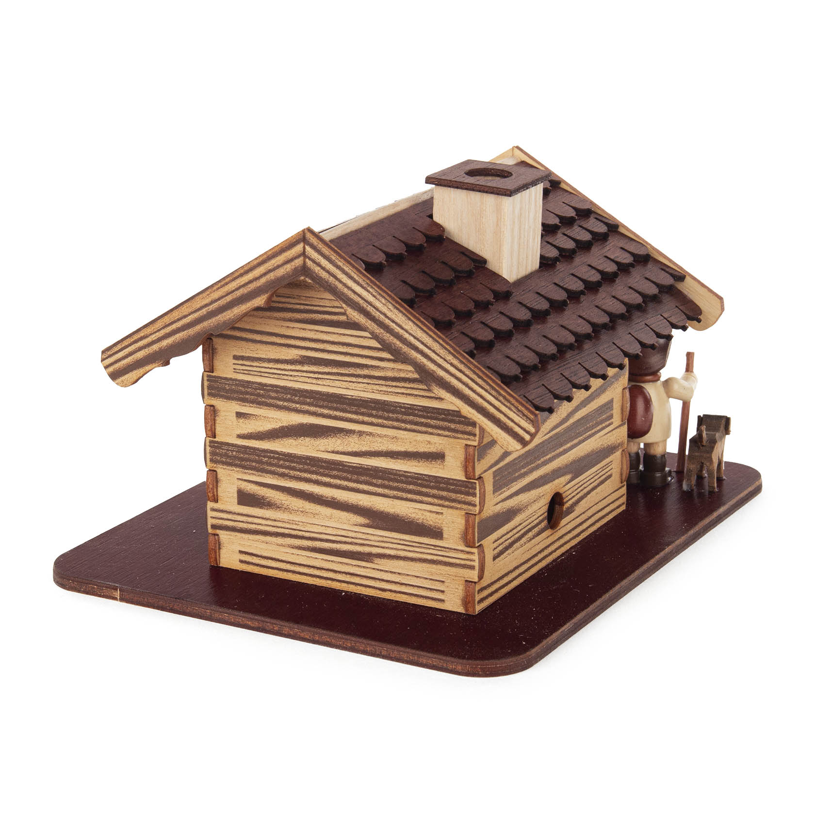 Holzfigur eines Jägers mit Hund steht vor einem aus Holz gefertigten Räucherhaus in Form eines Forsthauses.