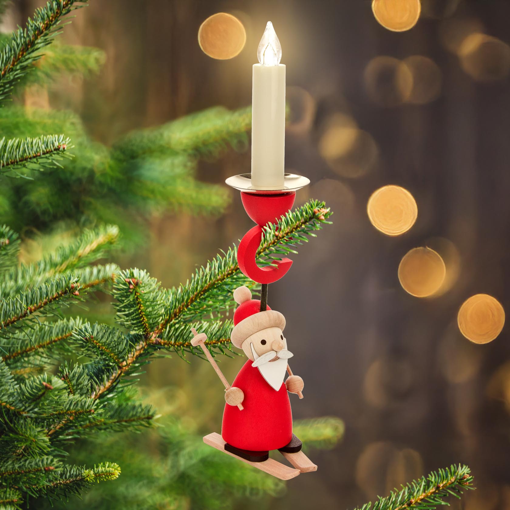 A wooden Santa Claus figure on skis, serving as a candle holder, hangs on a Christmas tree branch holding a lit candle.