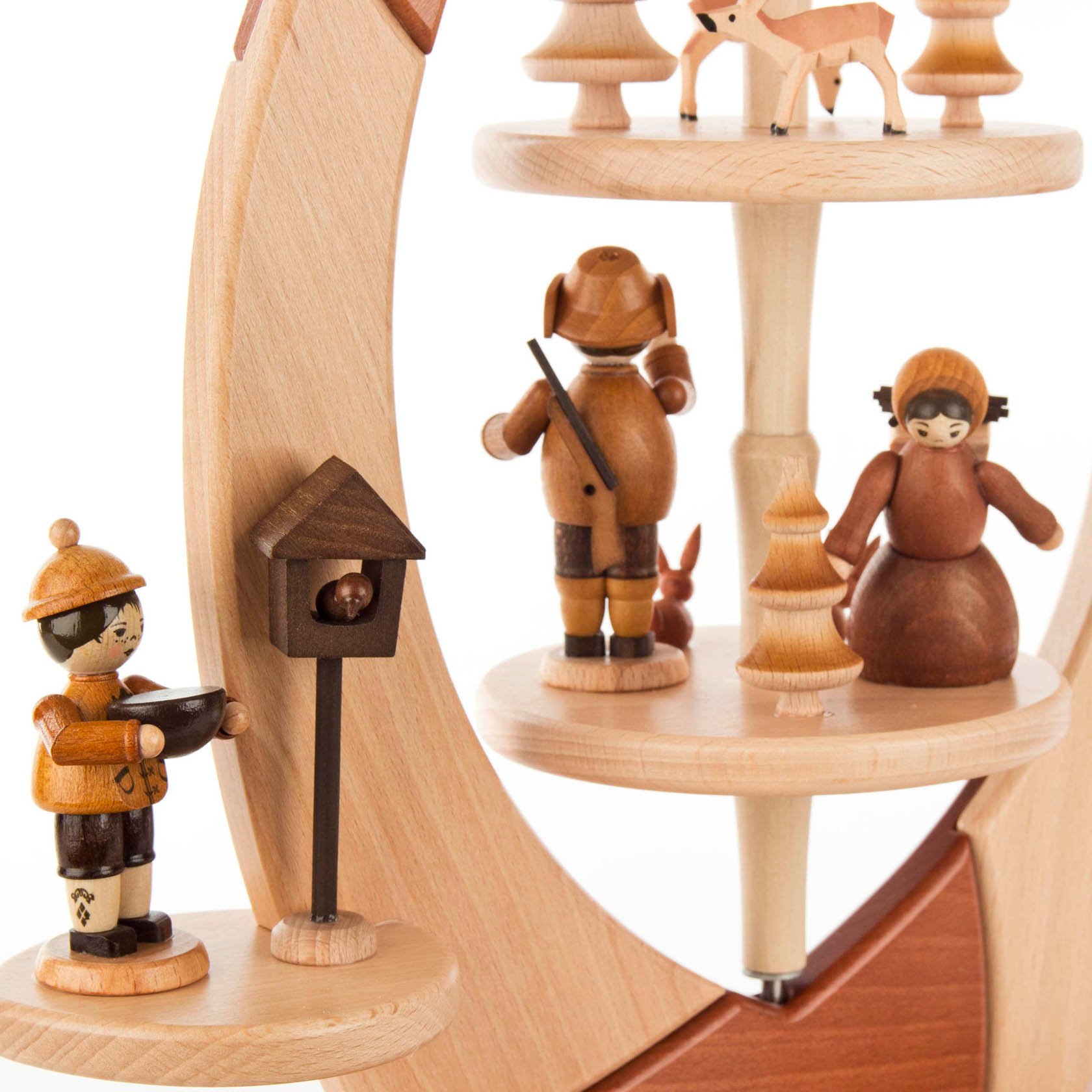 Holzpyramide in Form eines Segels mit geschnitzten Waldfiguren, darunter ein Förster, eine Frau, ein Reh und ein Vogelhäuschen.