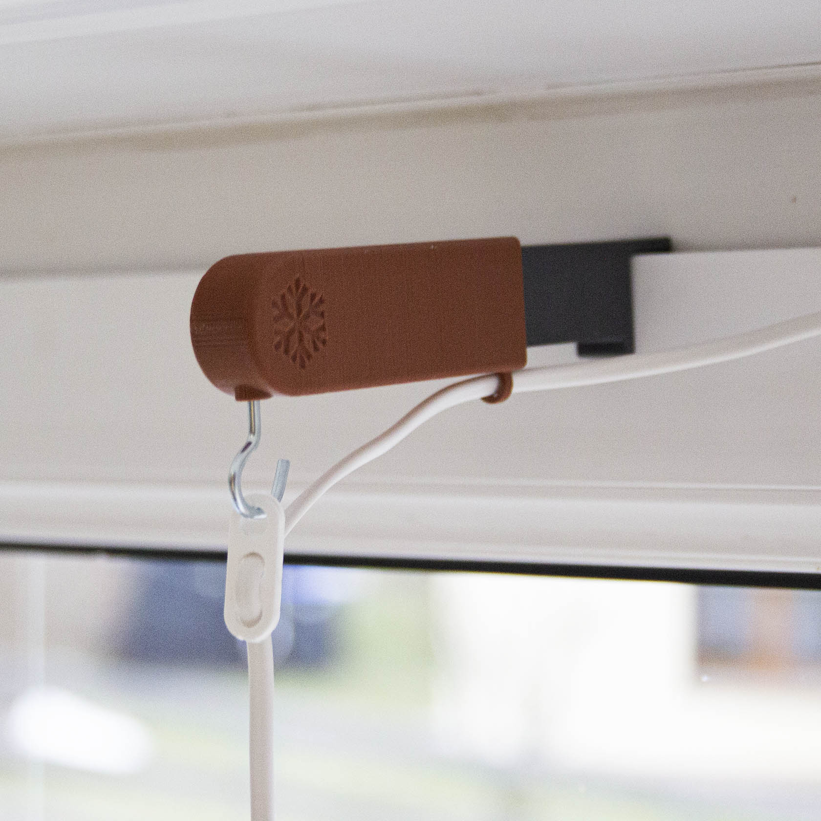 Brown adjustable star and lantern holder with cable management attached to a window frame.