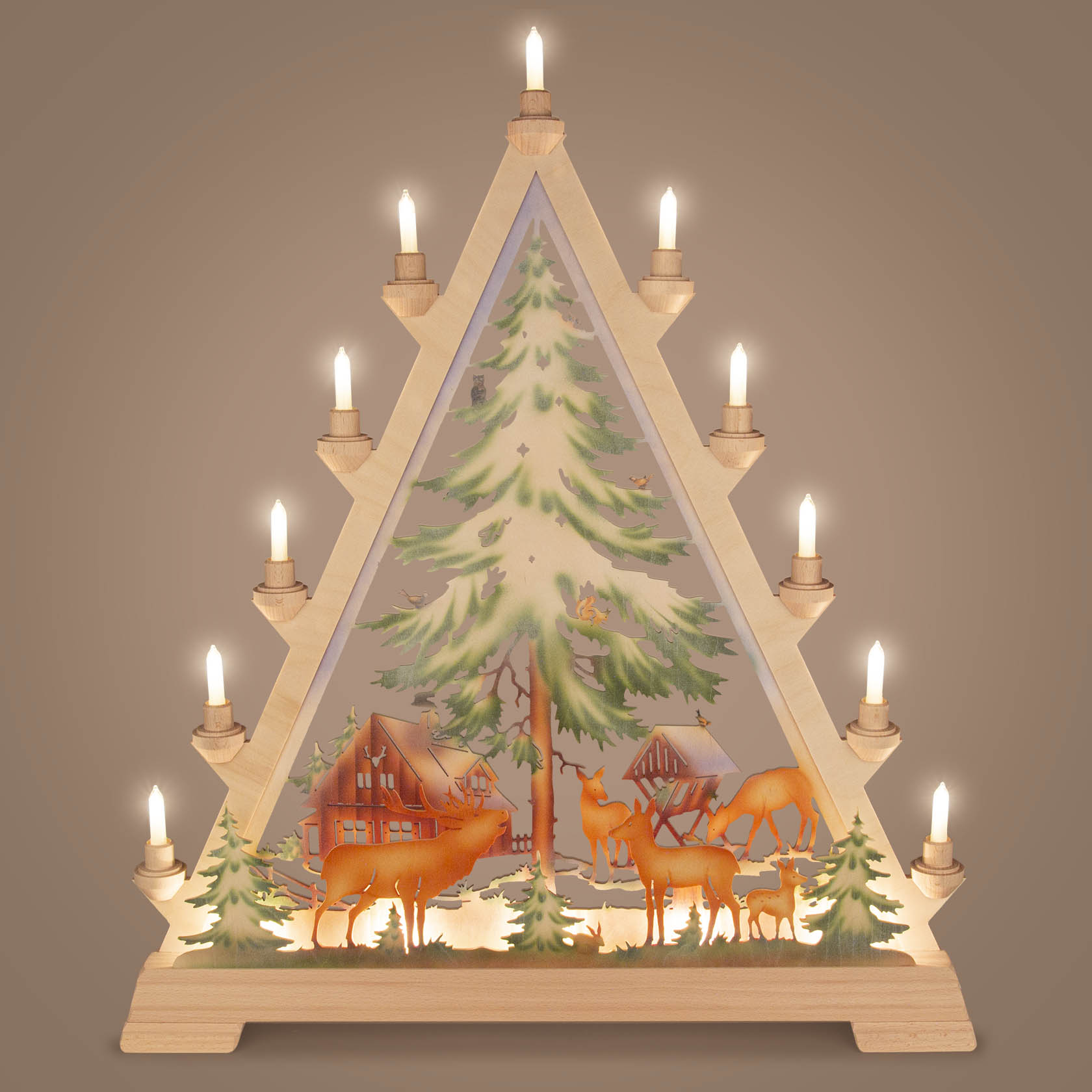 A wooden Christmas arch with a forest house, snow-covered trees, and deer, illuminated by several small lights atop the arch.