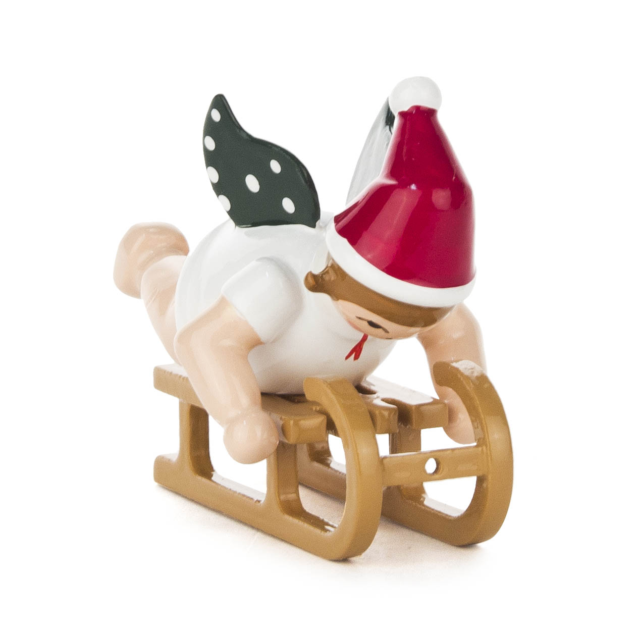 A wooden figure of an angel lying on a sled, wearing a red and white hat, with green wings featuring white dots. im Dregeno Online Shop günstig kaufen