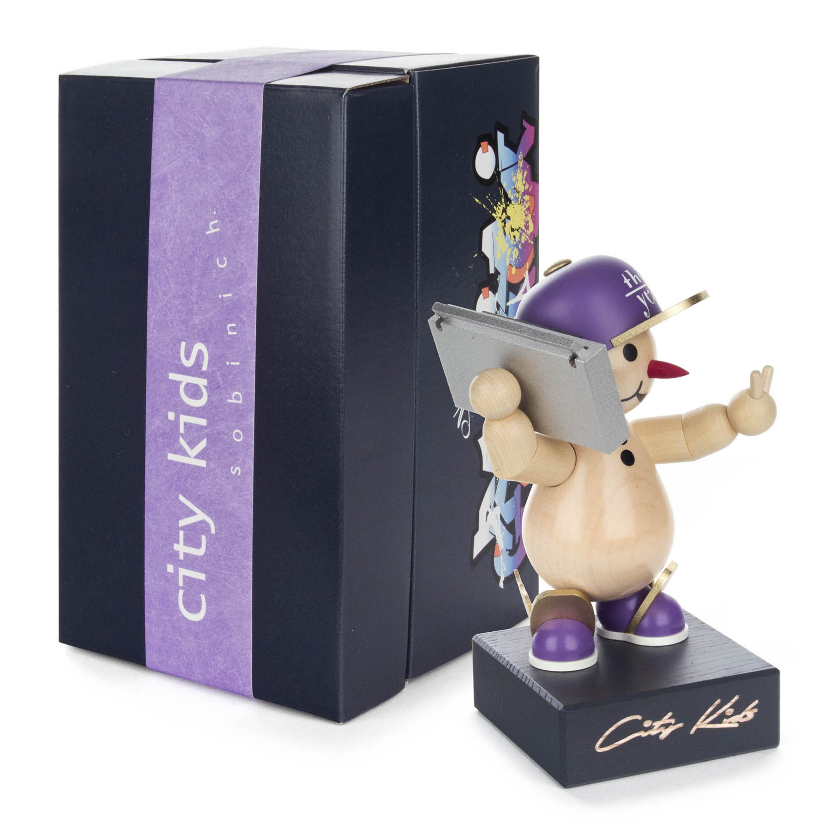 Holzfigur eines Schneemanns mit lila Baseballkappe, Sonnenbrille und Tablett in einer Hand, vor einer dunklen Box mit Schriftzug 'City Kids'.