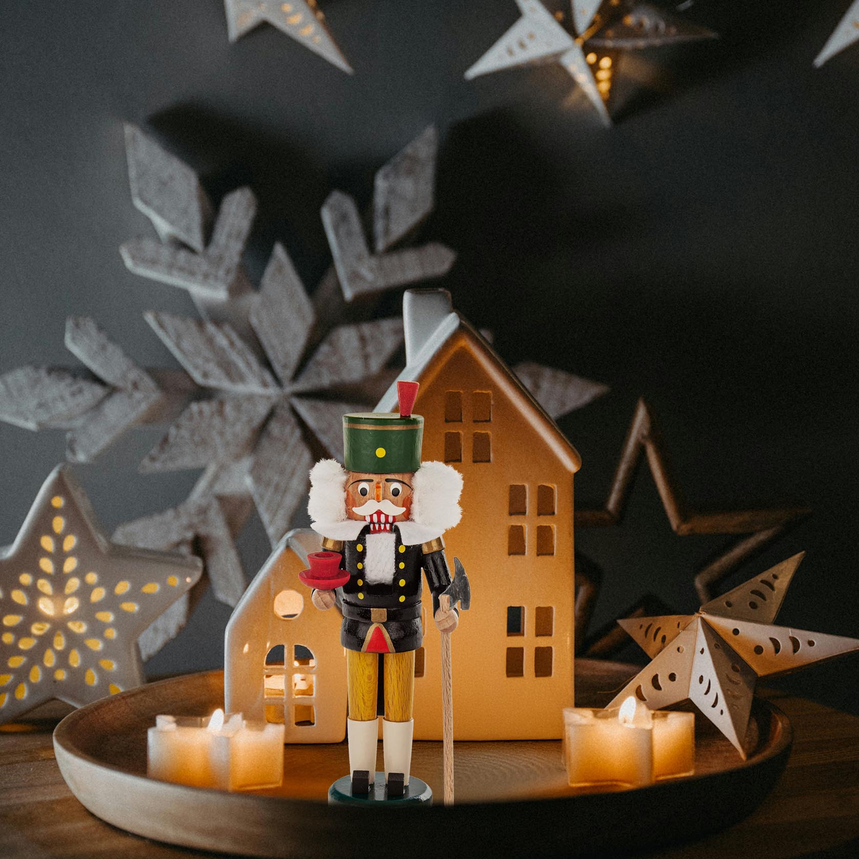 A colorful wooden nutcracker in the shape of a miner standing 14.5cm tall, with a green hat and black attire, holding a pickaxe.