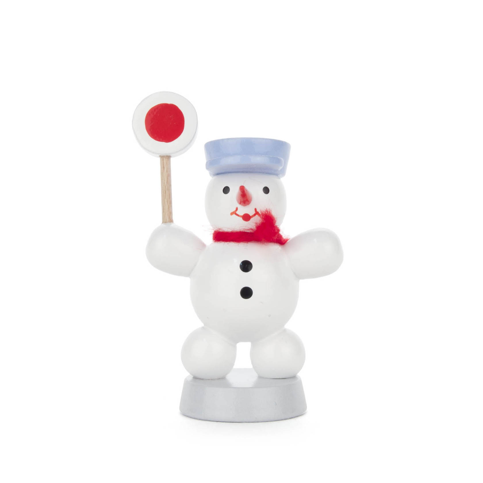 A small wooden snowman figure painted white, wearing a blue hat and red scarf, holding a railway signal with a red circle.