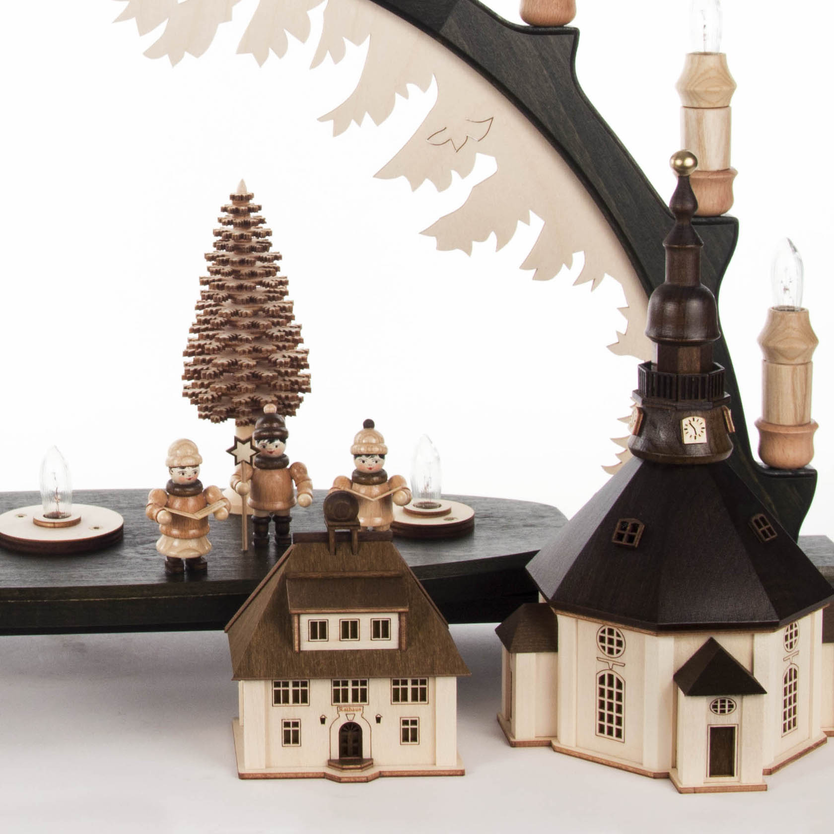 Black candle arch with Seiffen village and choir figures, featuring LED-lit buildings. Wooden figures stand near a church and a central Christmas tree.