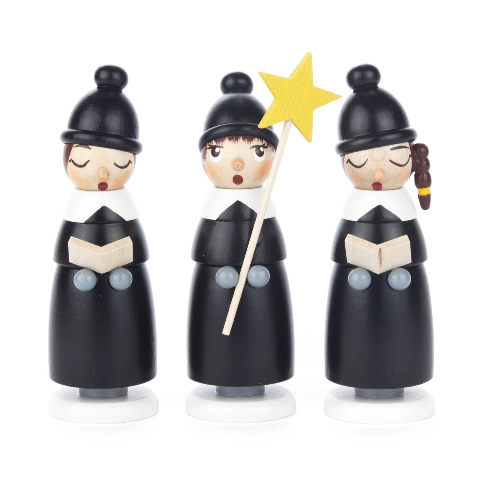Three black Kurrende figurines with white collars and hats, two holding books, and one holding a yellow star on a stick, symbolizing traditional carol singers.