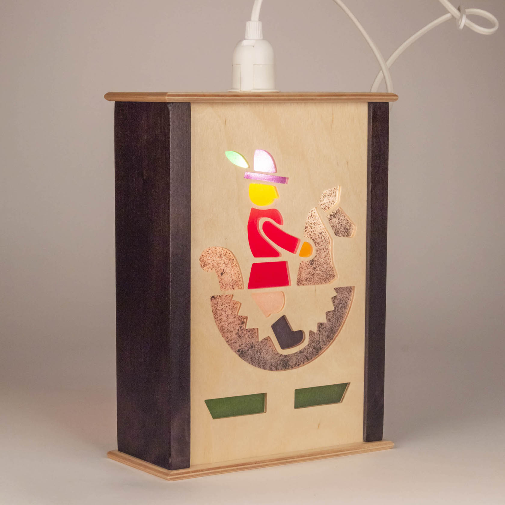 A small wooden window lantern featuring a cut-out design of a rider on a rocking horse, illuminated from behind.
