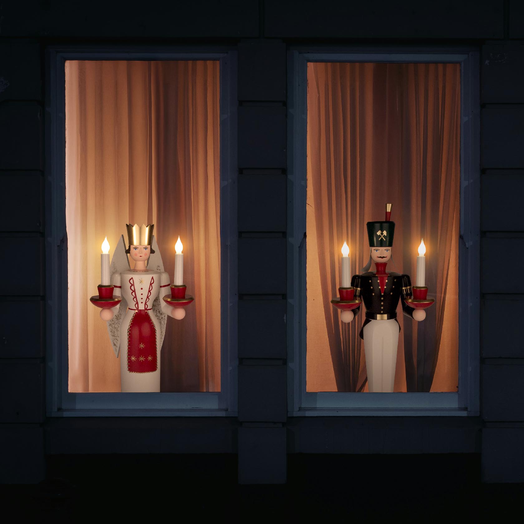 Zwei Lichterfiguren stehen in Fenstern, links eine Bergmännin in rotem Kleid mit zwei Kerzen, rechts ein Bergmann in Uniform mit zwei Kerzen.