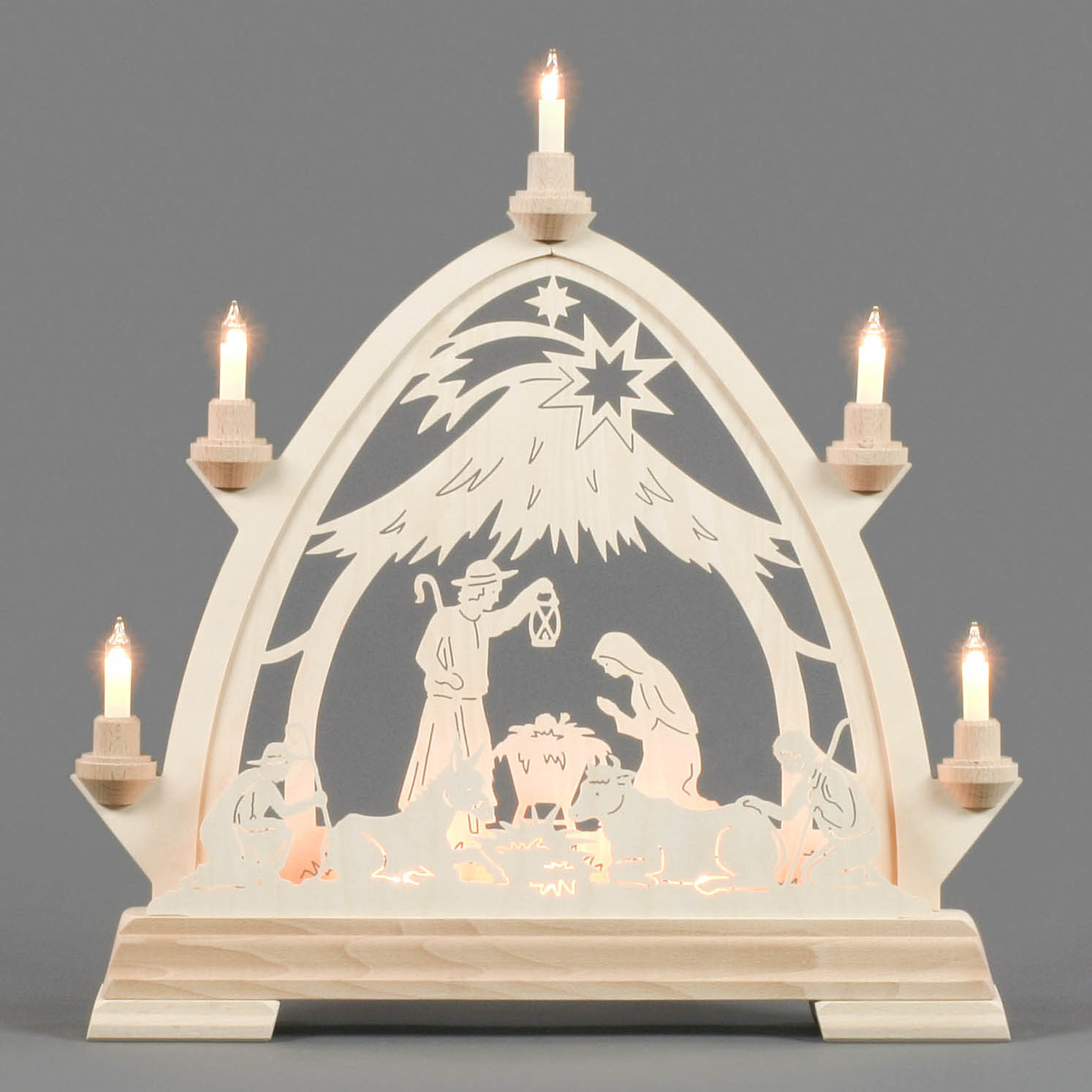 An electrically lit Gothic arch with a Nativity scene depicting Joseph, Mary, and baby Jesus under a star, surrounded by lit candles.