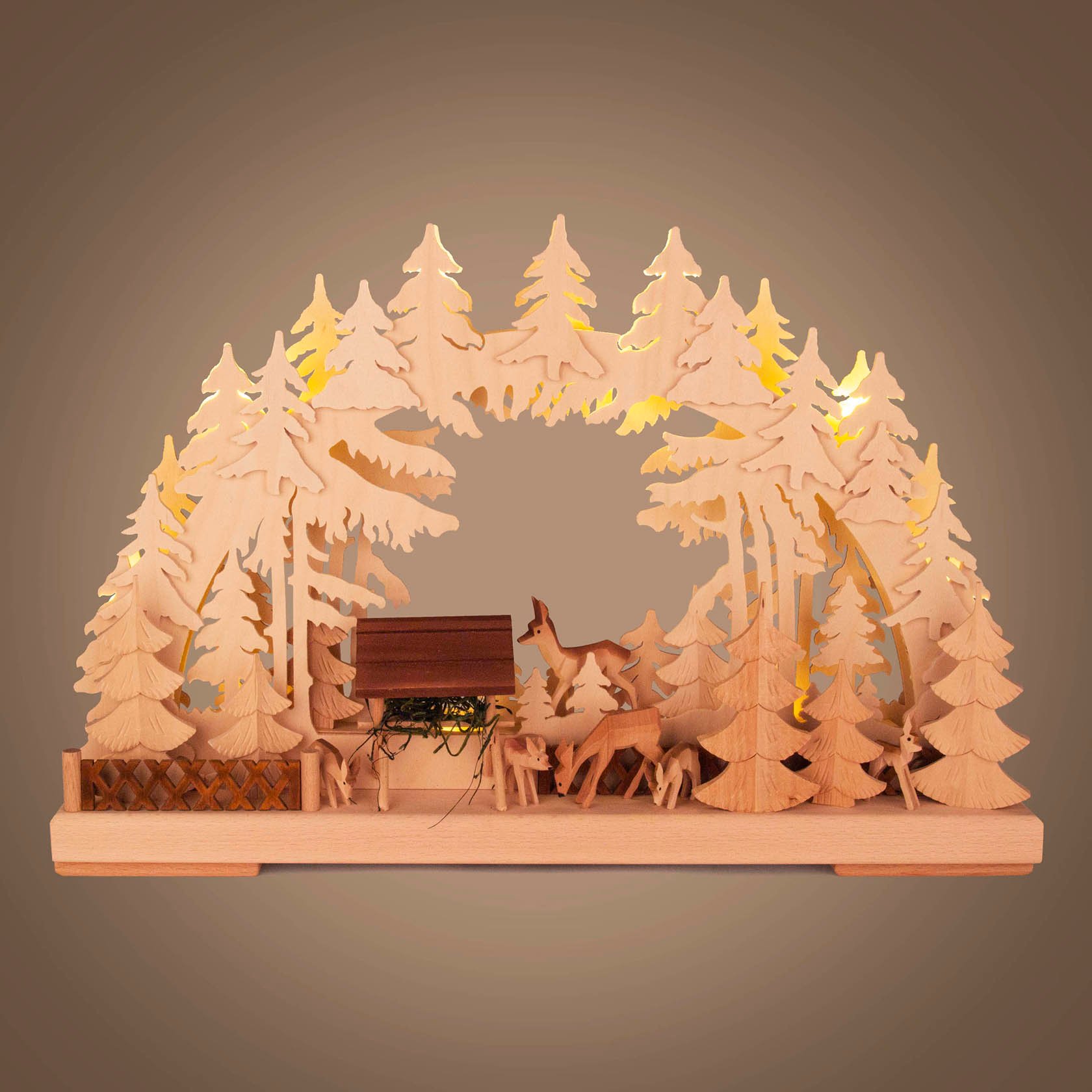 Ein kleiner Schwibbogen aus Holz mit indirekter Beleuchtung, zeigt eine Wildfütterungsszene mit Rehen im Wald.