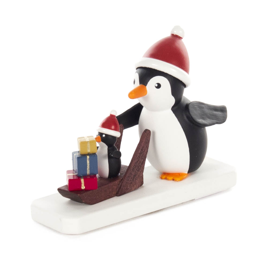 Zwei Pinguine mit Weihnachtsmützen. Ein großer Pinguin zieht einen Schlitten, auf dem ein kleiner Pinguin mit drei Geschenken steht. im Dregeno Online Shop günstig kaufen