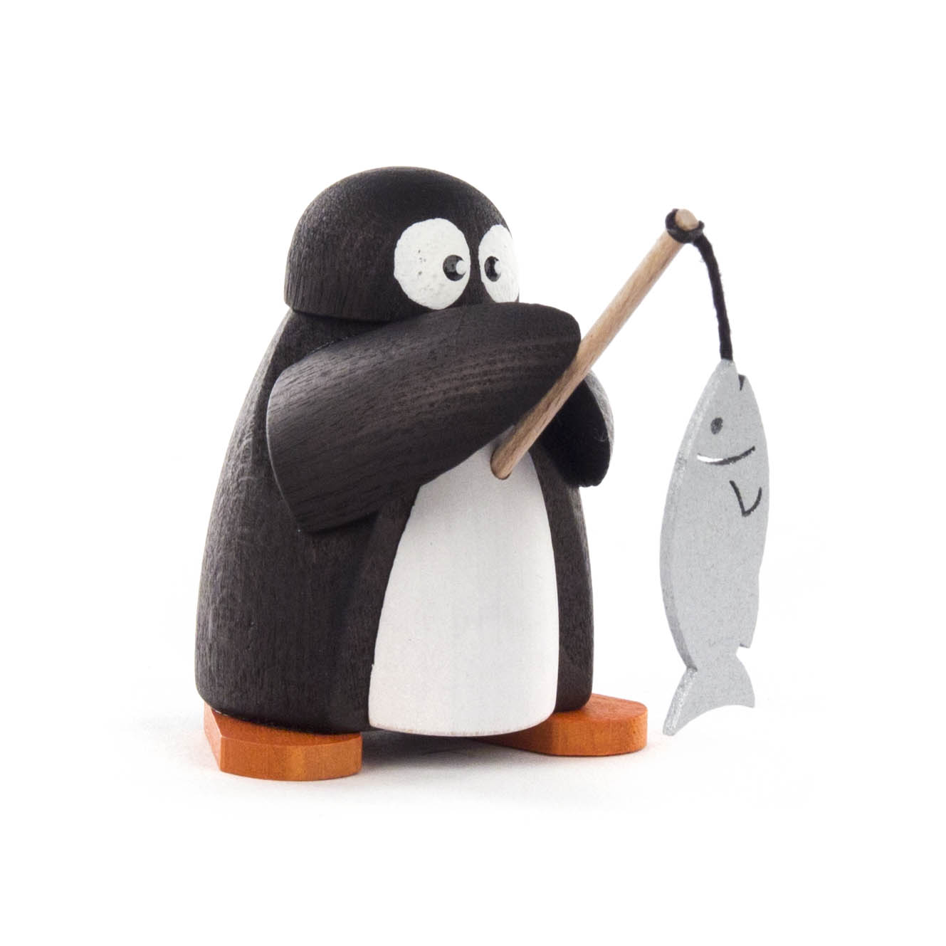 Holzfigur eines Pinguins mit weißen Augen und orangen Füßen, der mit einem Stock einen Fisch aus Holz hält.