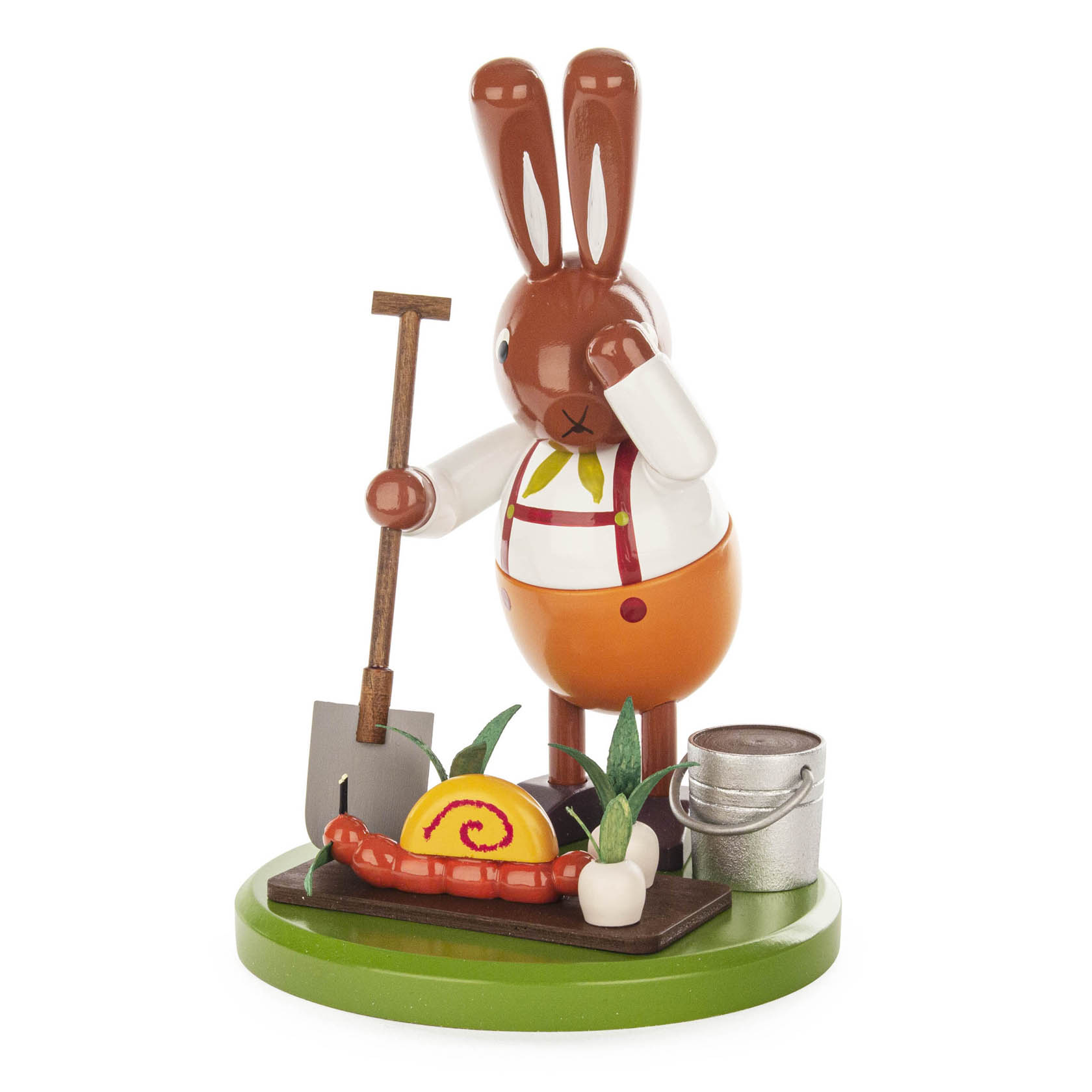 A wooden figurine of a rabbit in overalls, holding a spade, standing next to a snail and a metal bucket on a green base.