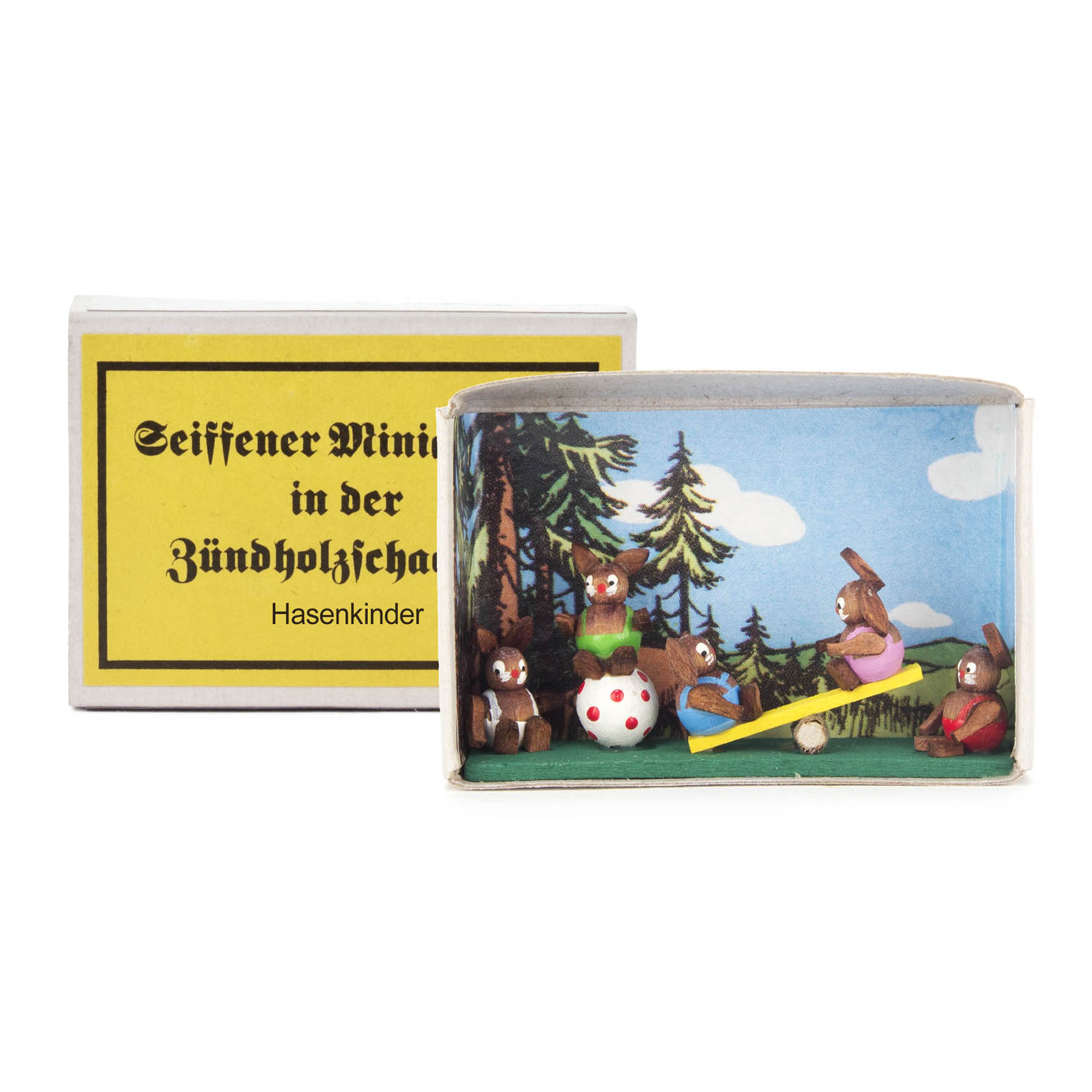 A matchbox displaying a miniature scene with handcrafted rabbit figures playing on a seesaw and sitting on a dice. im Dregeno Online Shop günstig kaufen