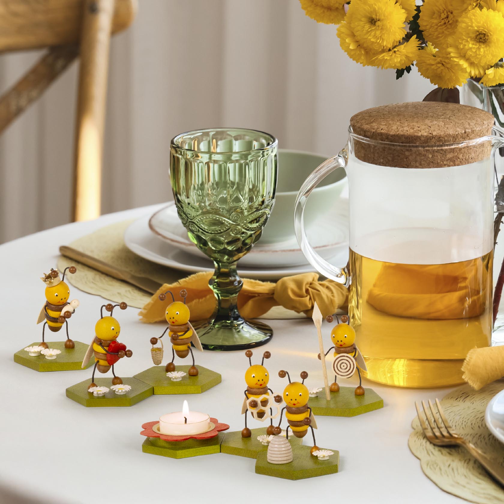 Sechs Teelichthalter aus Holz in Form von Bienenfiguren, die eine Wabe und Blumen emulieren. Ein Teelicht ist auf einem blumenförmigen Halter platziert.