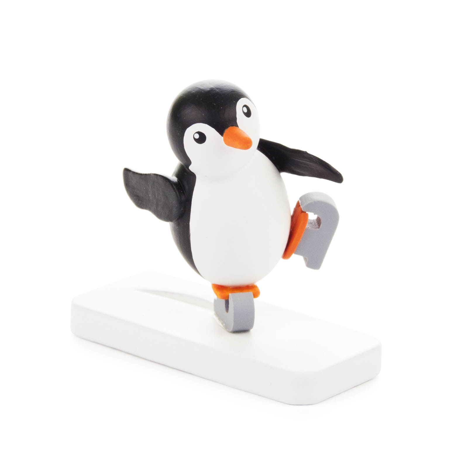 Kleine Pinguinfigur in Eislaufpose mit einem Bein in der Luft, platziert auf einem weißen Sockel. im Dregeno Online Shop günstig kaufen