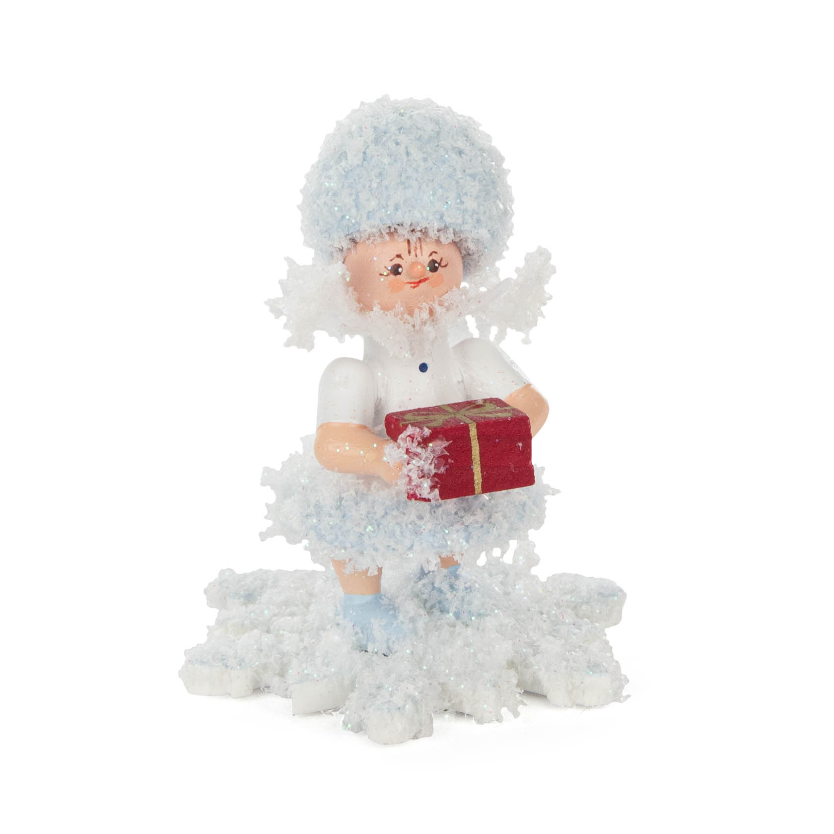 Eine niedliche Schneeflöckchen-Figur hält ein rotes Geschenk mit goldener Schleife in den Händen, umgeben von glitzerndem Schnee. im Dregeno Online Shop günstig kaufen