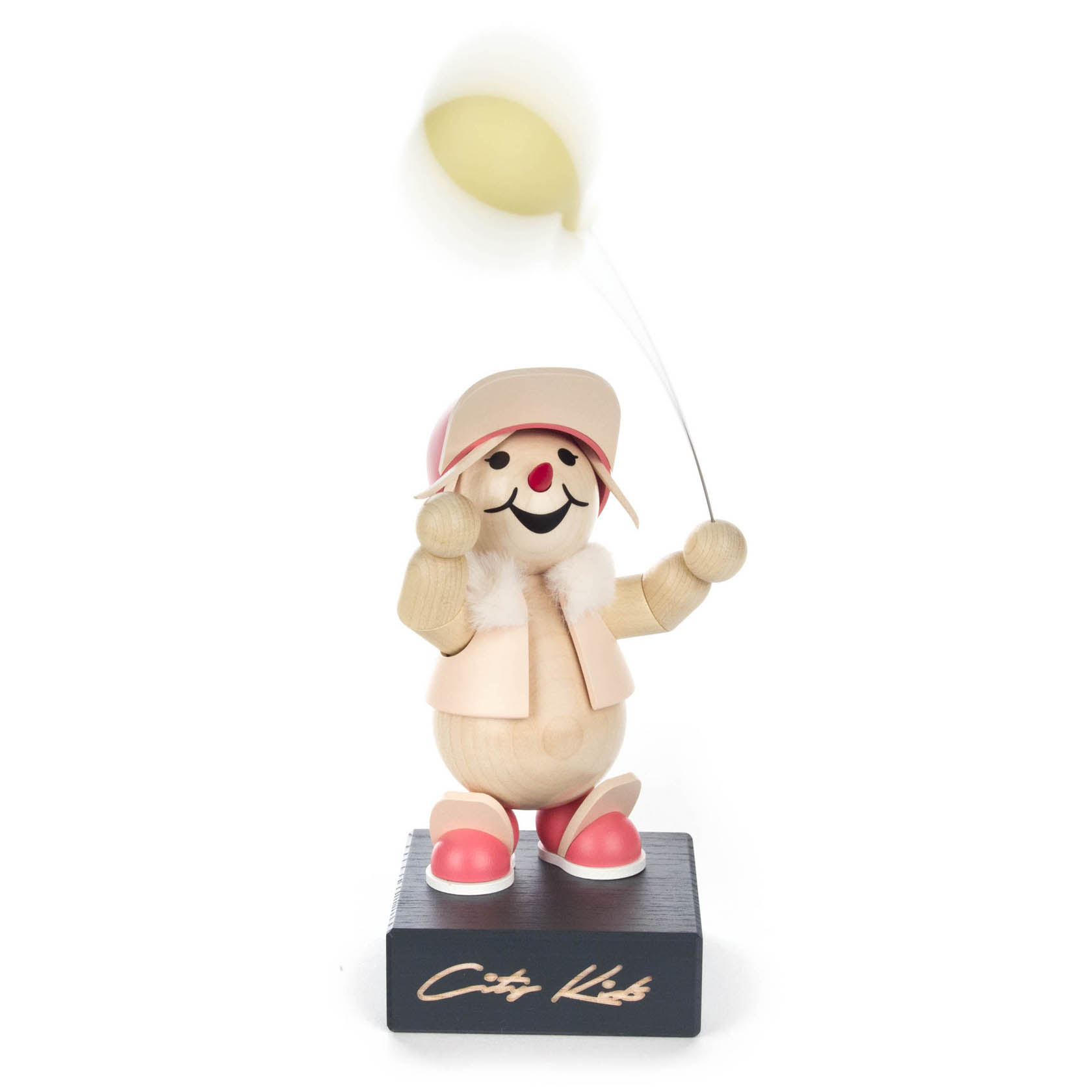Wooden figurine named 'City Kids' Abbie, with a smiling face, wearing a pink hat and jacket, holding a yellow balloon.