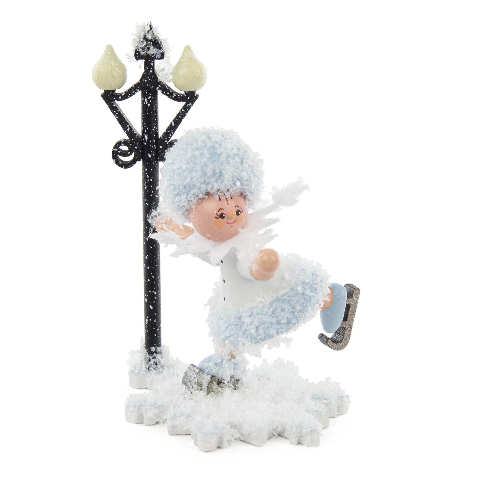 A cheerful snowflake character with a blue fuzzy coat and hat is ice skating joyfully next to a vintage-style street lamp, set on a snowy base. im Dregeno Online Shop günstig kaufen
