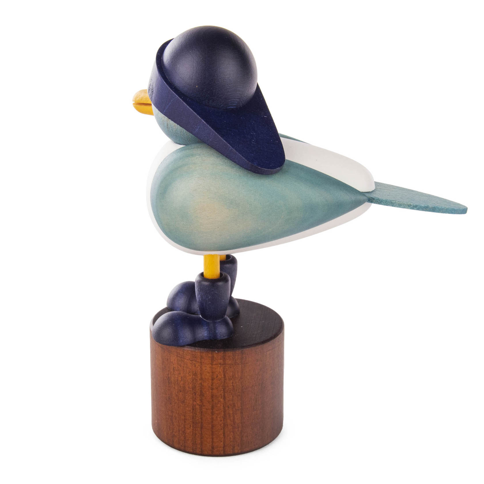 Holzfigur einer Möwe mit blauem Südwester stehend auf einem runden Holzsockel. Die Möwe hat einen blauen Schnabel und einen blauen Kopf.